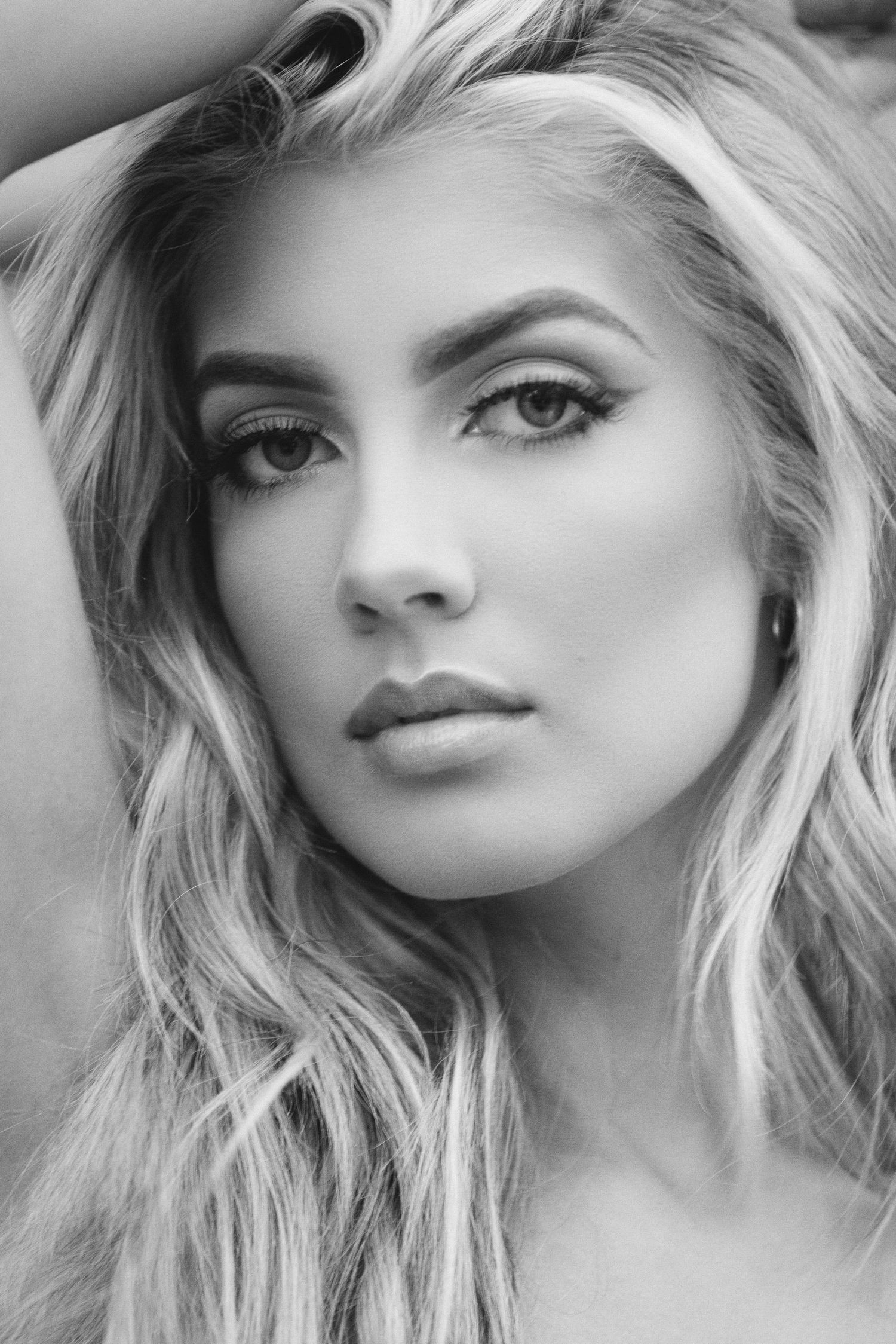 Black and white glamour portrait featuring soft waves of blonde hair, dramatic eye makeup, and perfectly sculpted features.