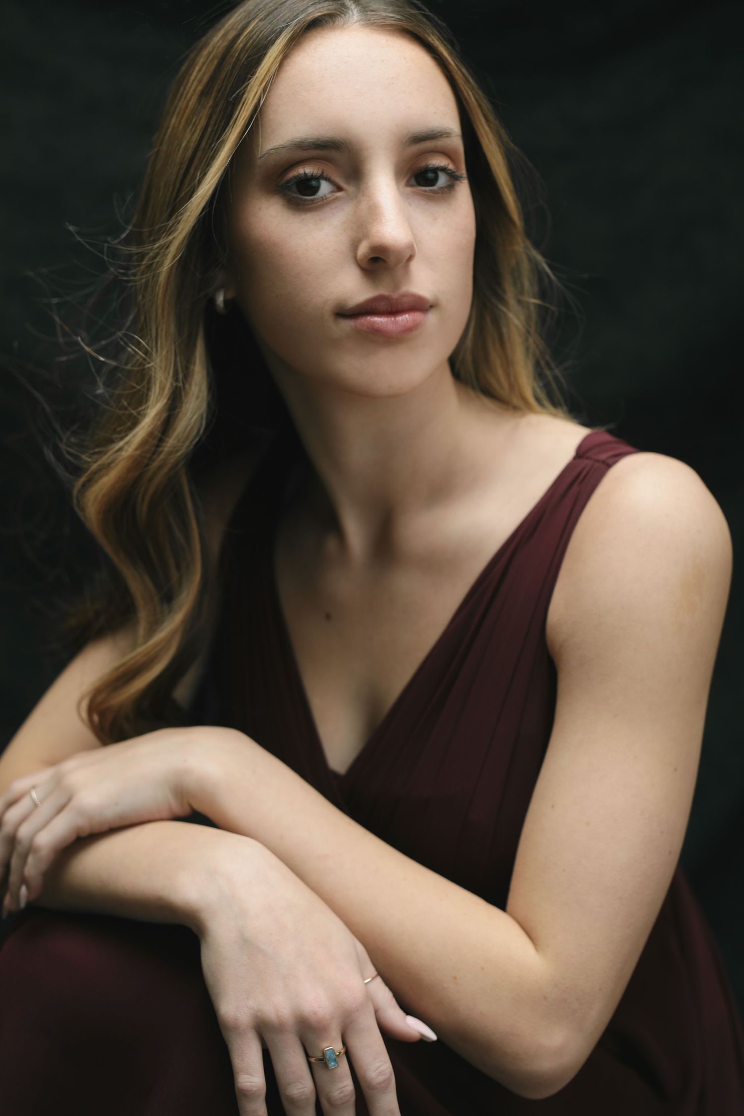 Studio portrait photo series showing a person in a maroon sleeveless top posing against a dark background.