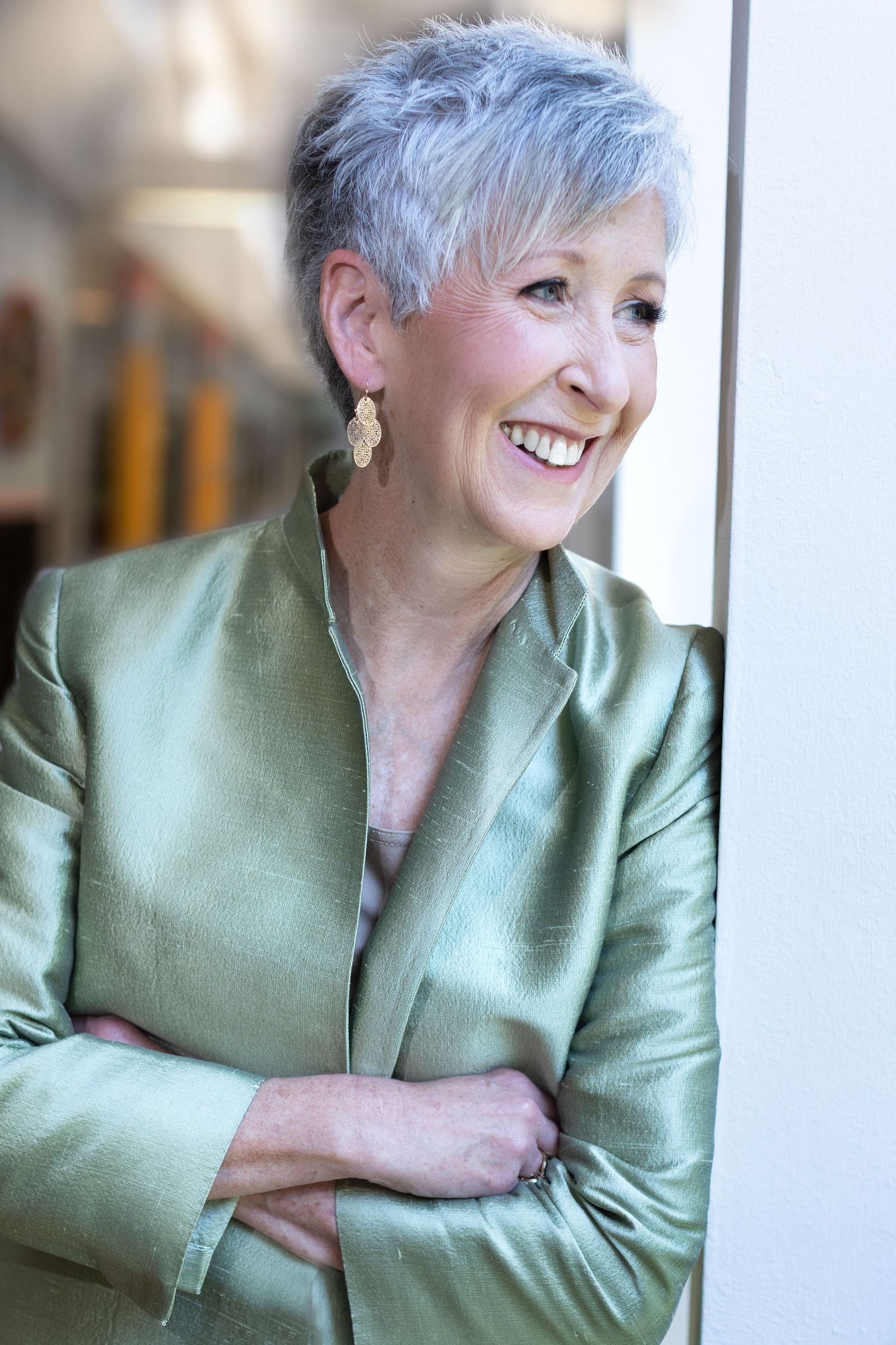 A portrait series showing joyful expressions while wearing a mint green silk blazer against a light background.