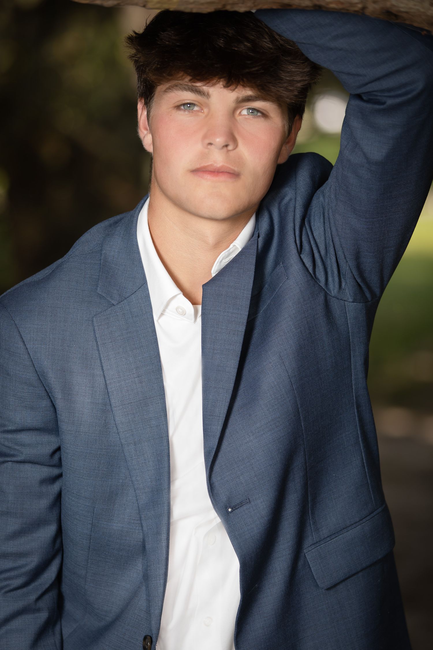 Portrait of a person posing outdoors wearing a navy blue suit jacket and white dress shirt.