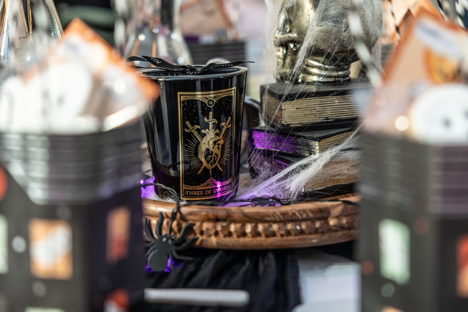 Decorative black glass with gold design sits in woven basket surrounded by glassware and purple lighting effect.