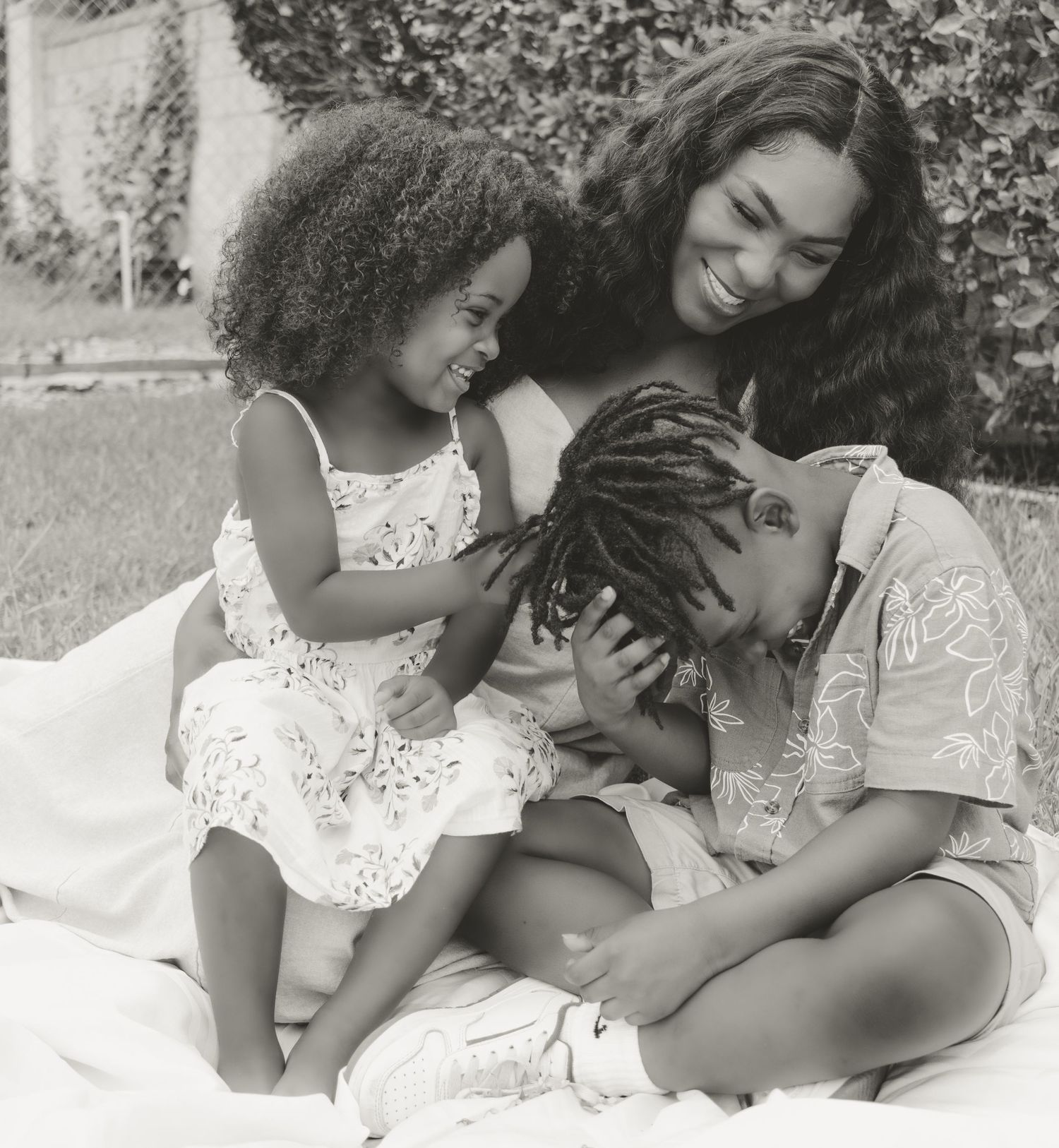 A tender black and white moment of family affection while relaxing together on a blanket outdoors.