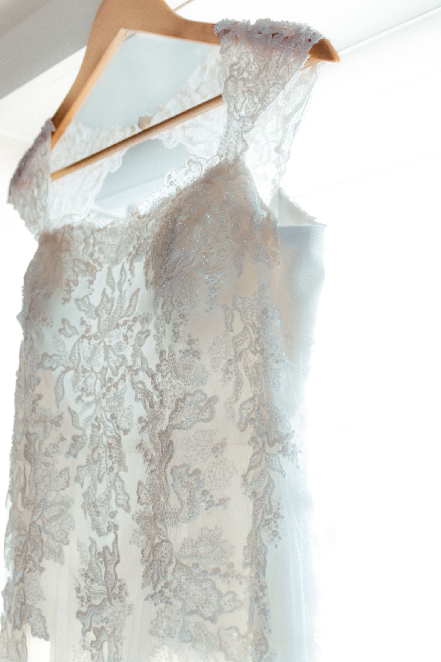 Detailed view of an elegant white lace wedding gown with intricate floral patterns.