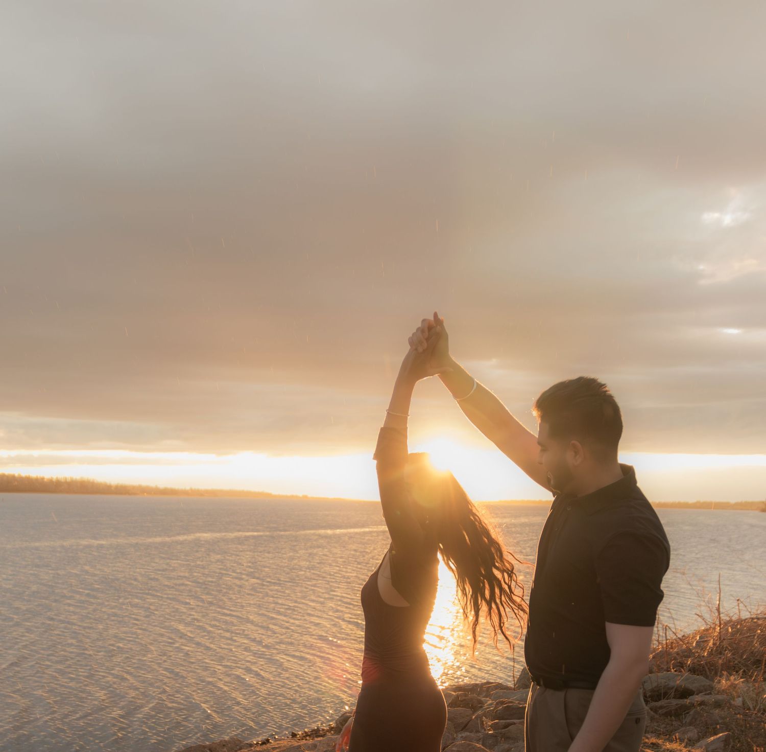 Silhouetted couple dancing together against a golden sunset backdrop.