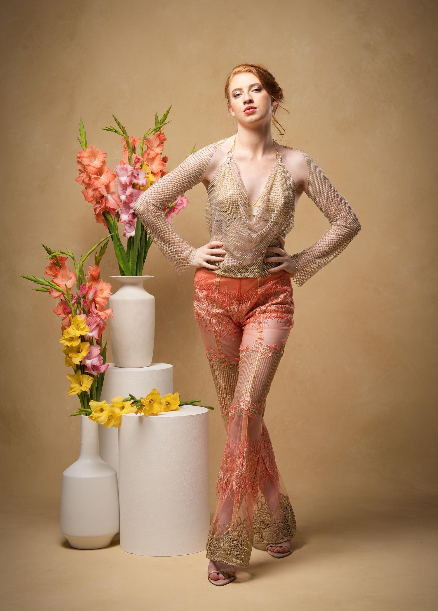 Elegant spring fashion editorial featuring soft peach gown and floral arrangements on white geometric pedestals.