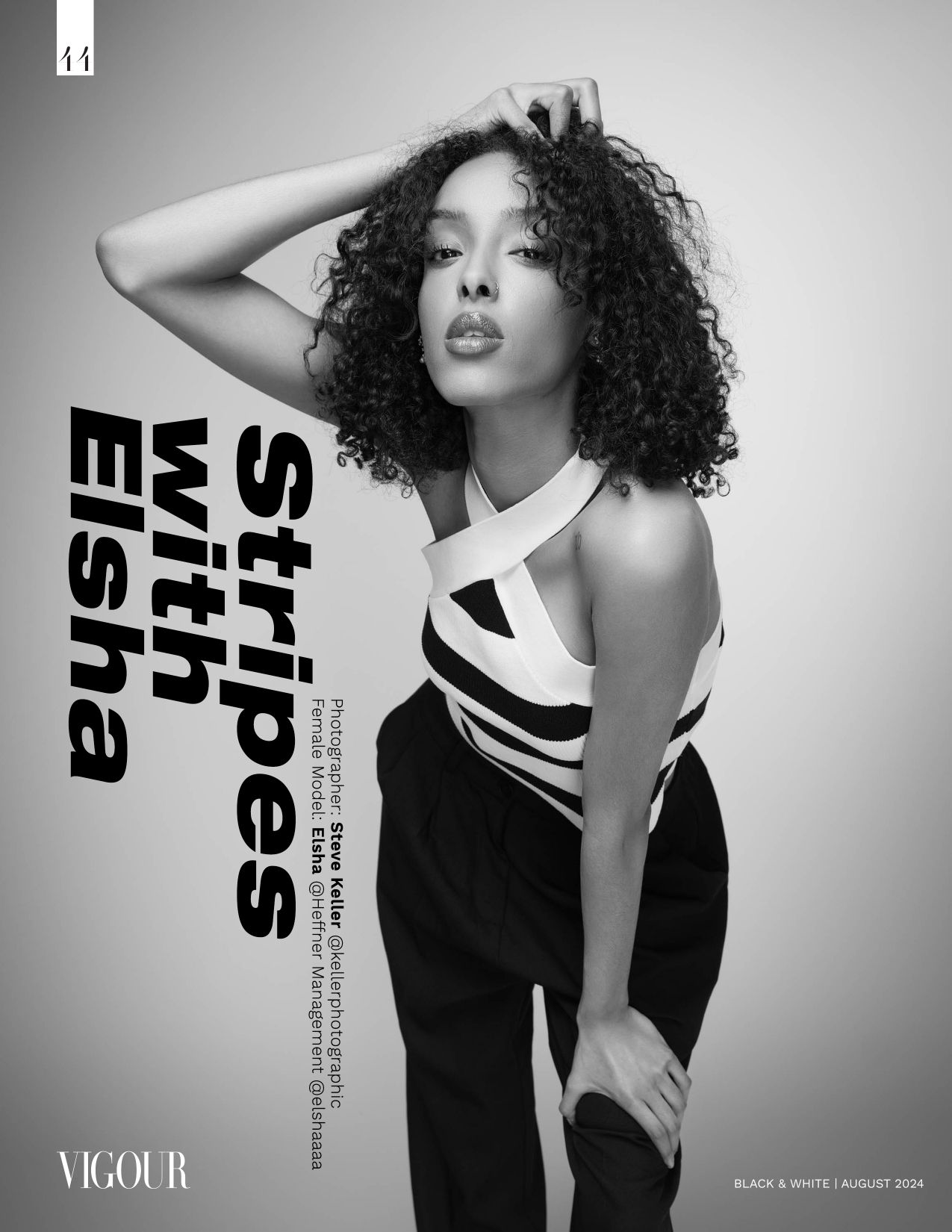 Black and white fashion portrait showing a model in a black outfit with white stripes against a gray background.