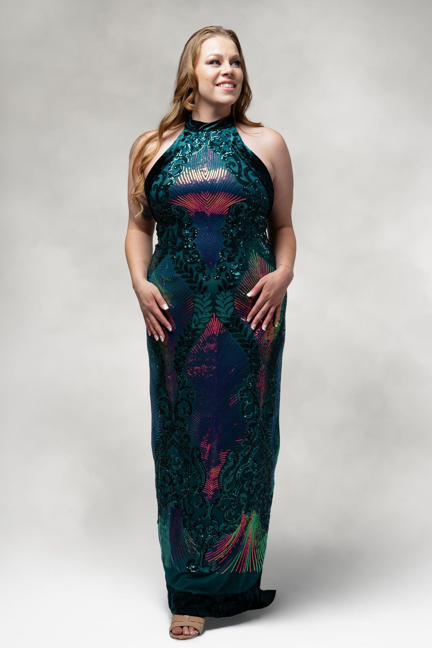 A formal studio portrait showing an elegant green sequined halter-neck evening gown.