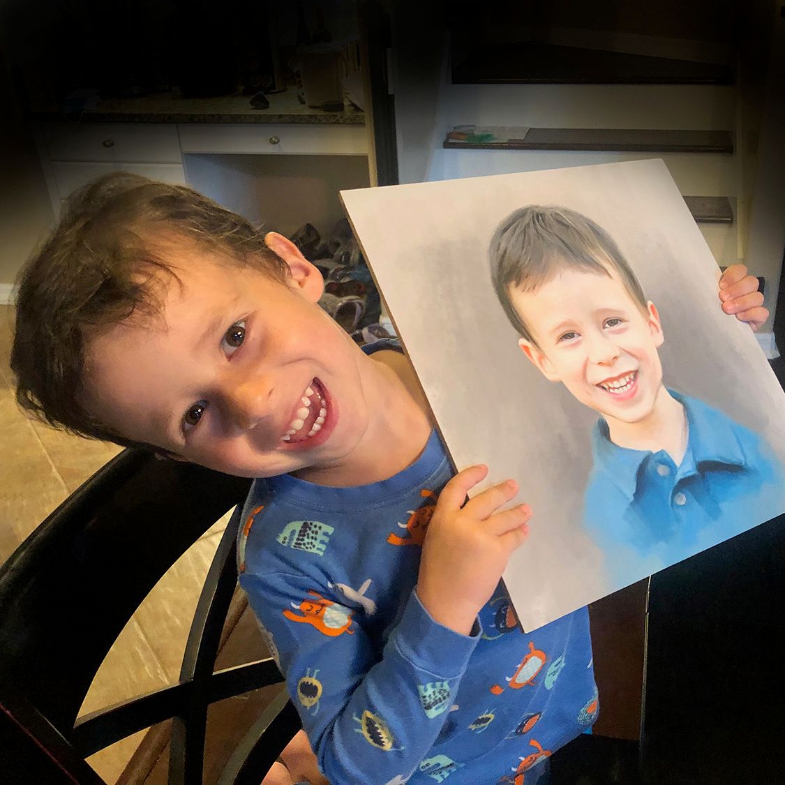 A delighted young boy holding his portrait painting proudly with a big smile on his face.