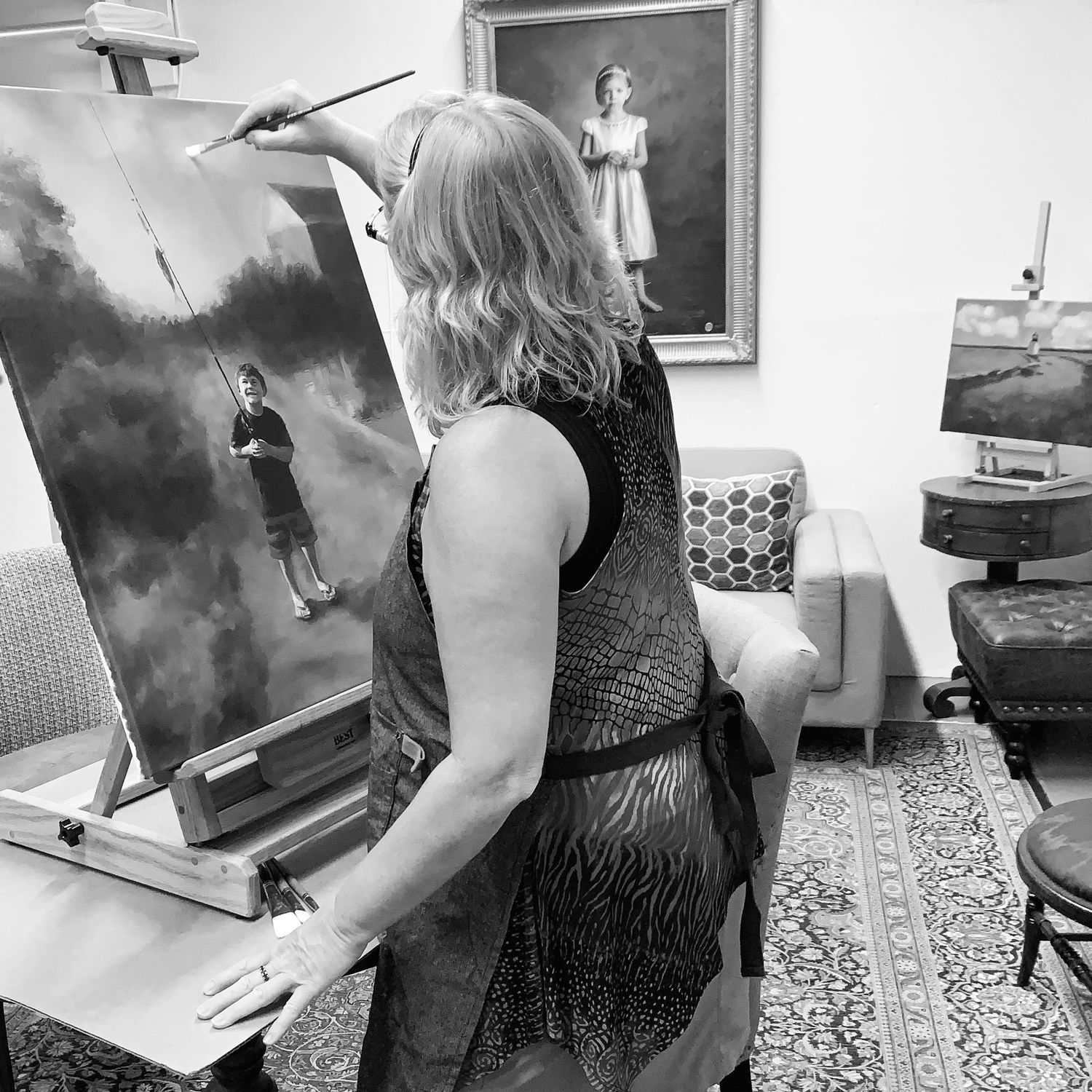 Black and white photo showing artist Bobbie Bush working at an easel in her studio.