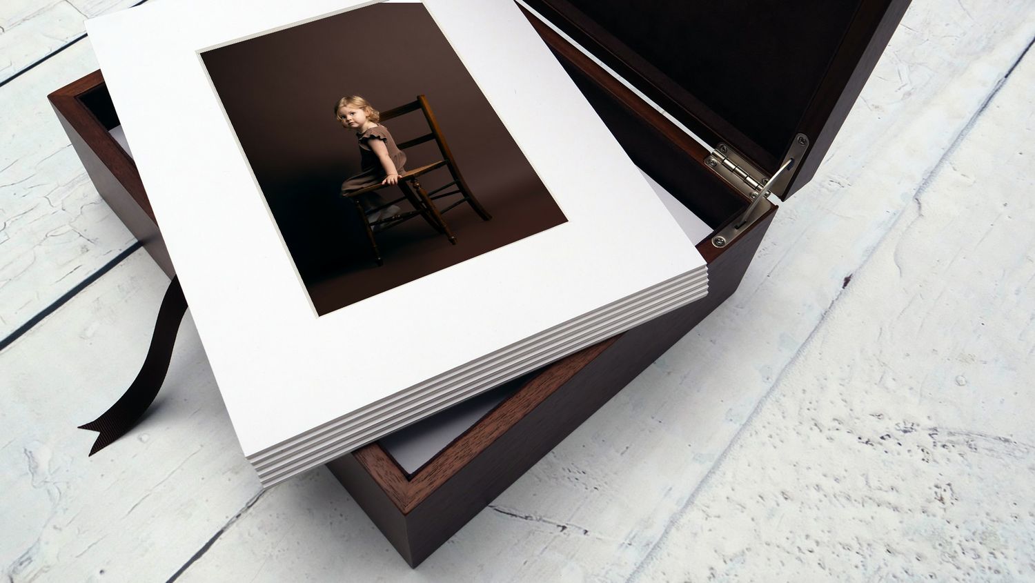 Fine art photography folio box with white matted prints and black presentation box on white wooden surface.