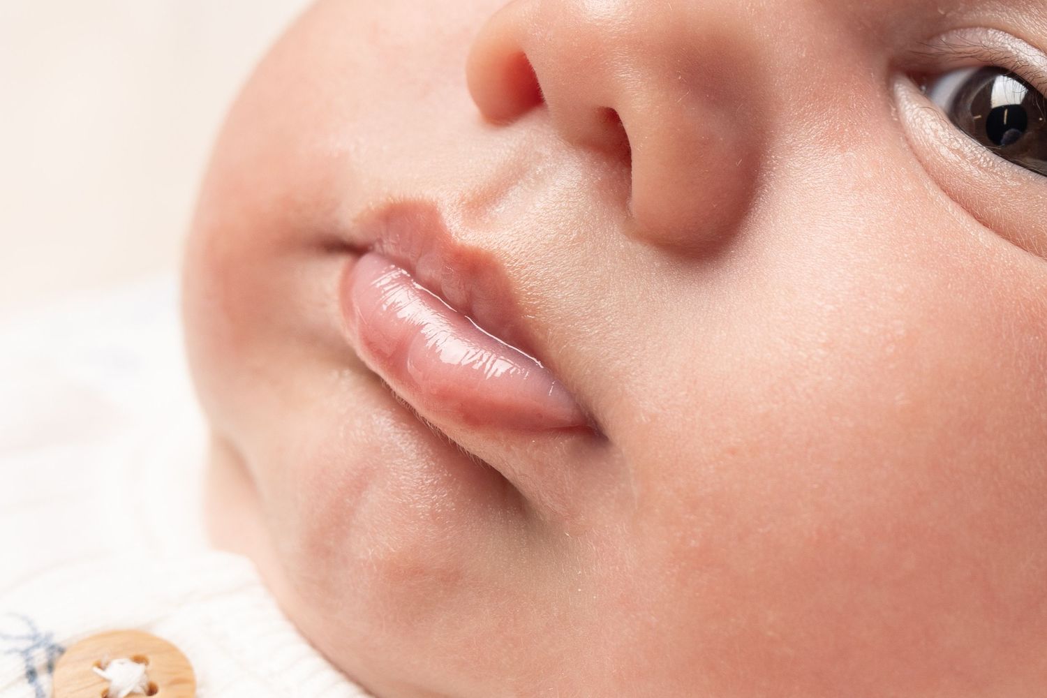 Close-up beauty shot showing natural pink glossy lips and smooth skin texture.