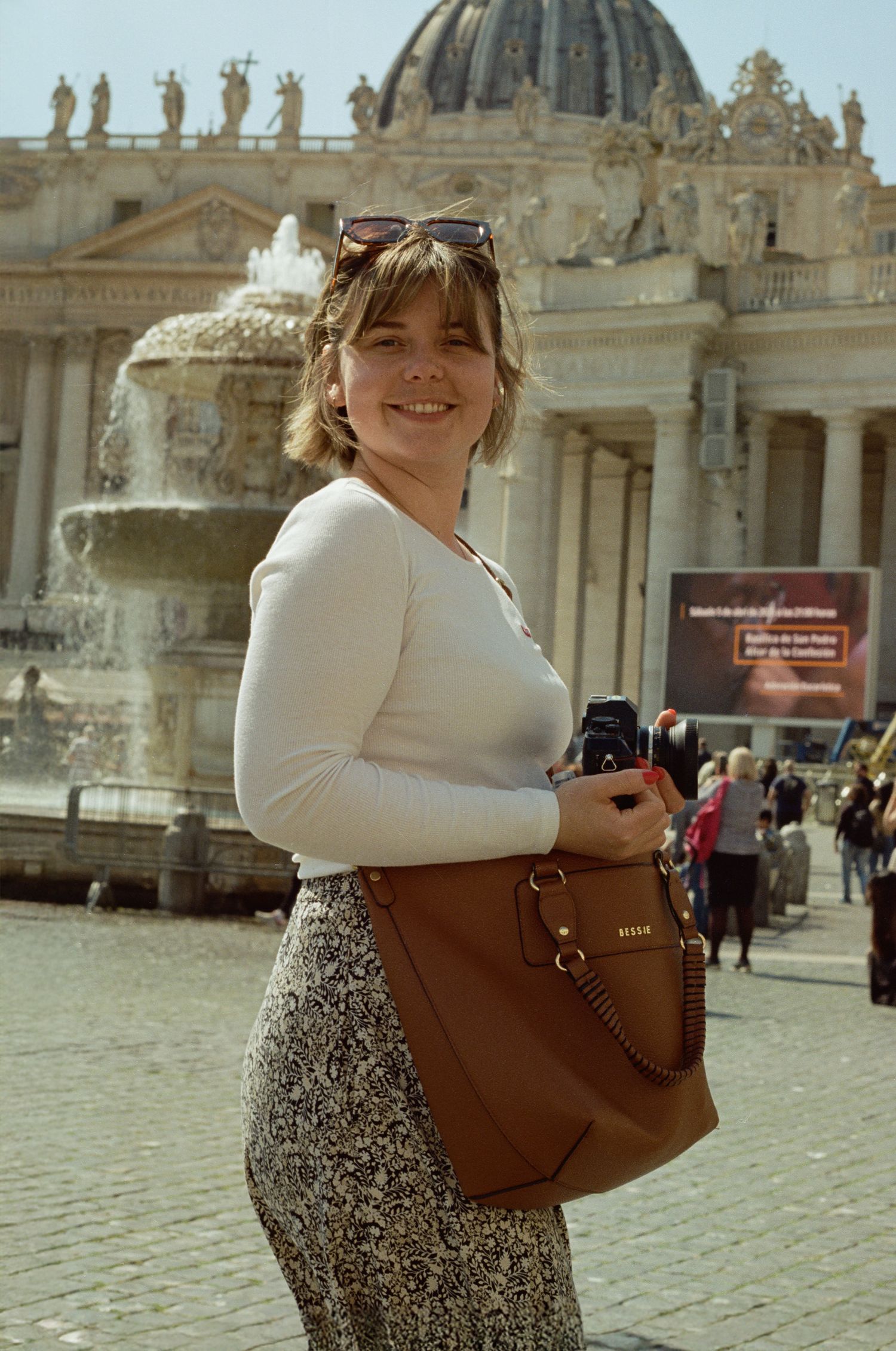 Tourist standing in Saint Peter's Square at the Vatican with the iconic basilica dome and statues in the background.