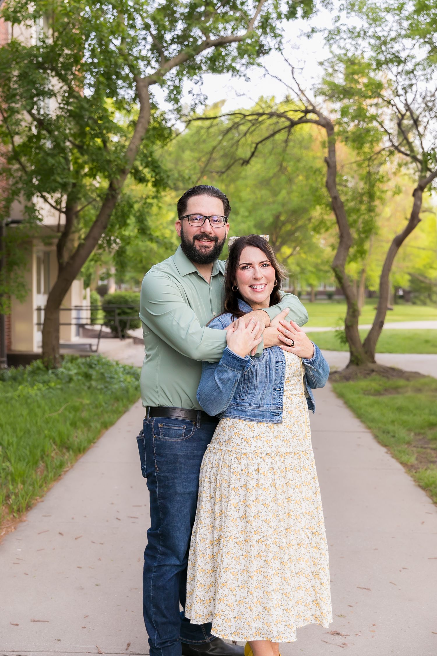 A couple shares a romantic embrace while standing on a tree-lined path during a spring couples photoshoot in Pittsburg KS and Joplin MO.