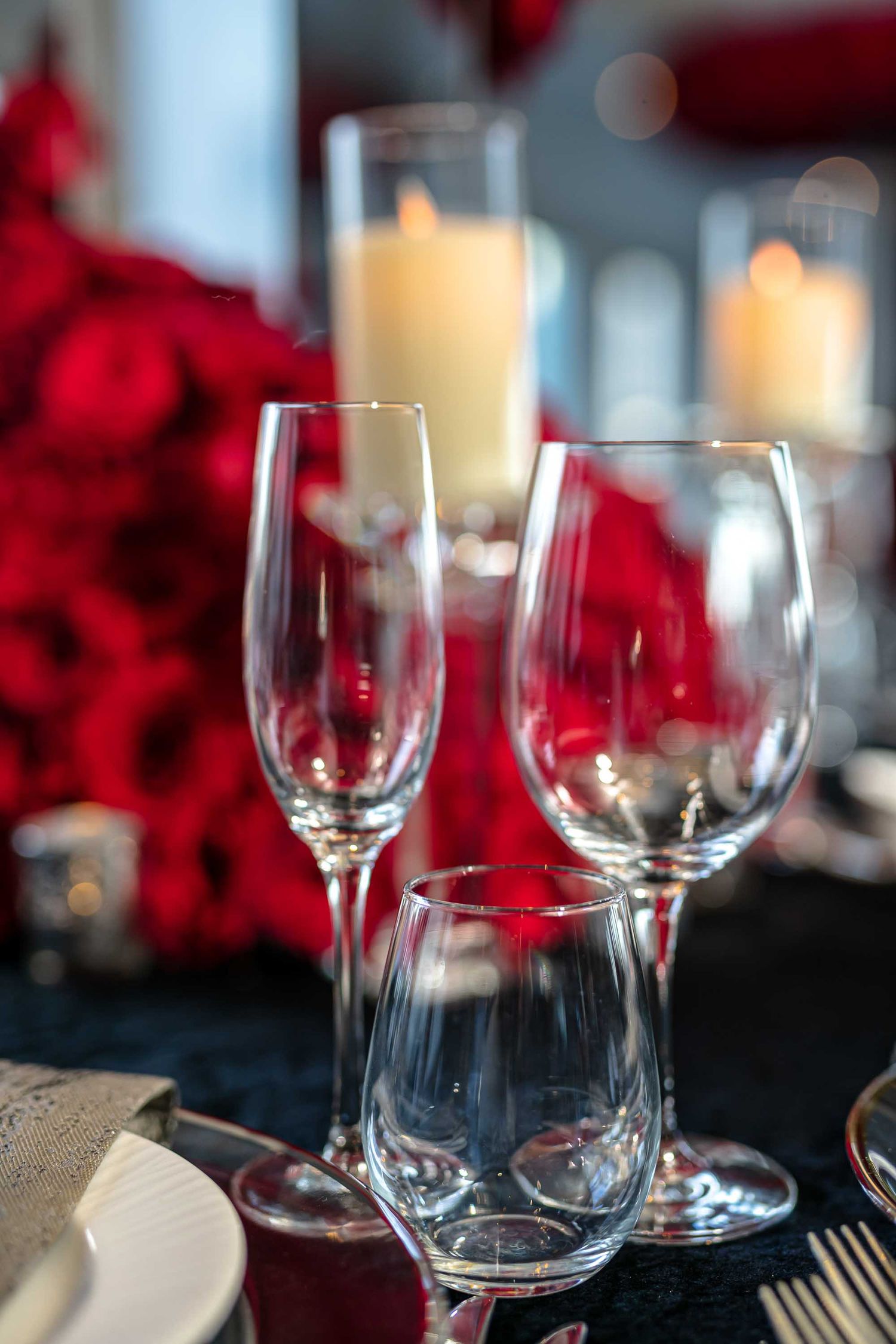 Elegant wine glasses and candlelight setting with vibrant red roses create a romantic dining atmosphere on the Seafair Mega Yacht in Miami.
