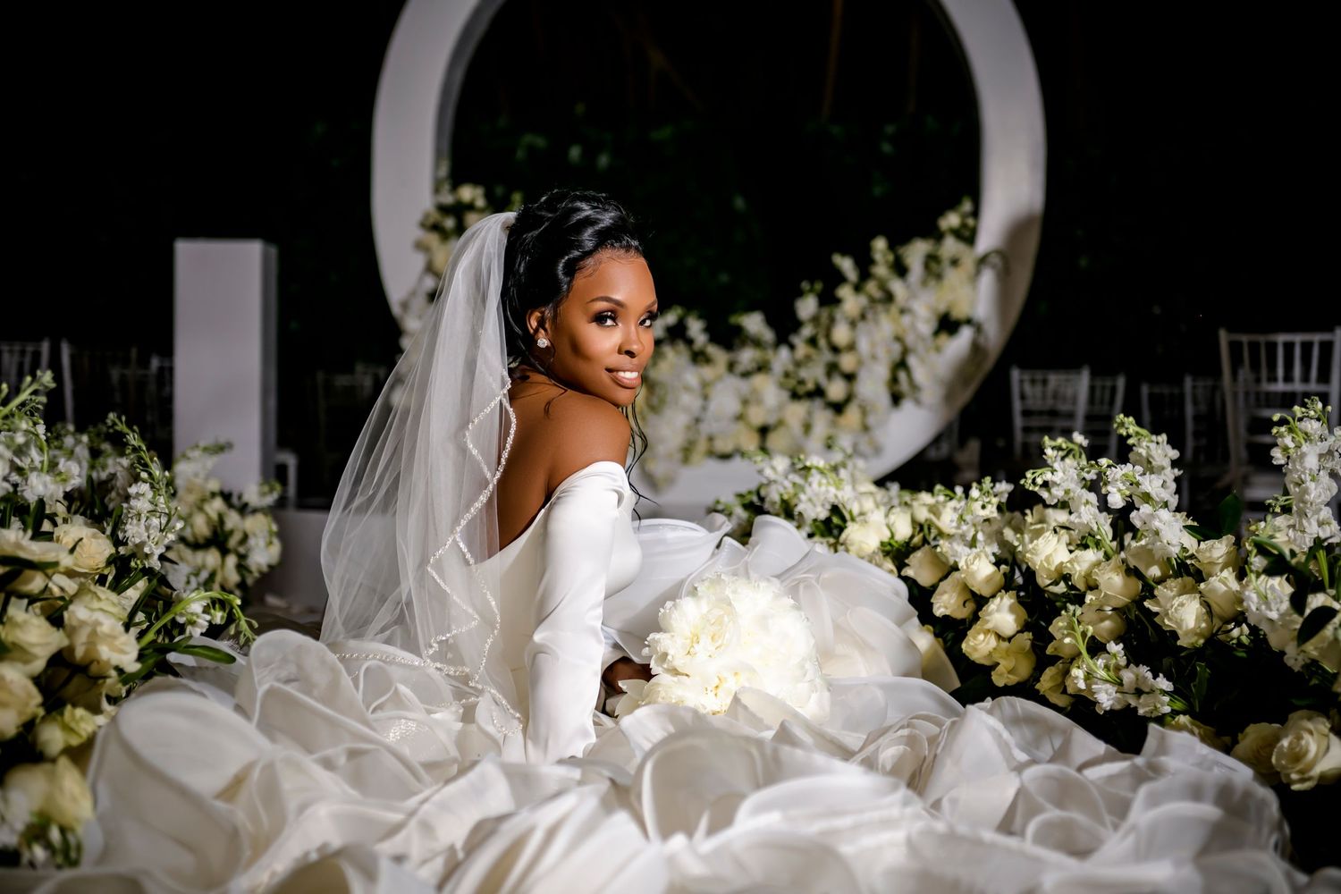 An elegant wedding reception setup with white floral arrangements and dramatic black lighting.