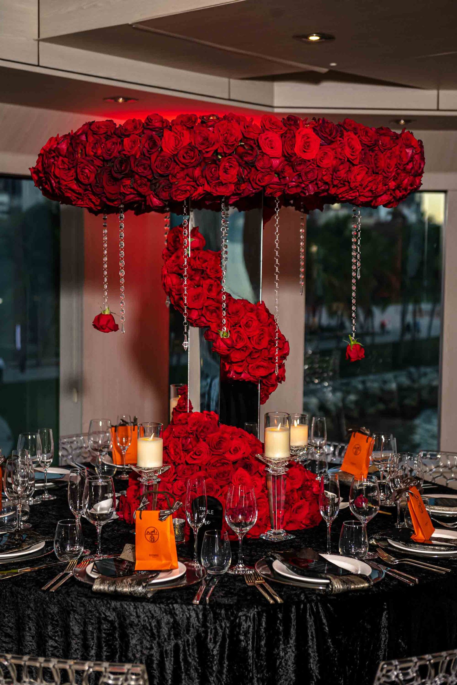 Dramatic red rose centerpiece with hanging crystals over black tablecloth at formal dinner setting on the Seafair Mega Yacht in Miami.