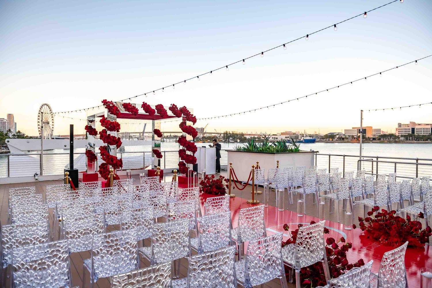 Rooftop wedding venue with red and white balloon arch and clear chairs overlooking city views on the Seafair Mega Yacht in Miami.