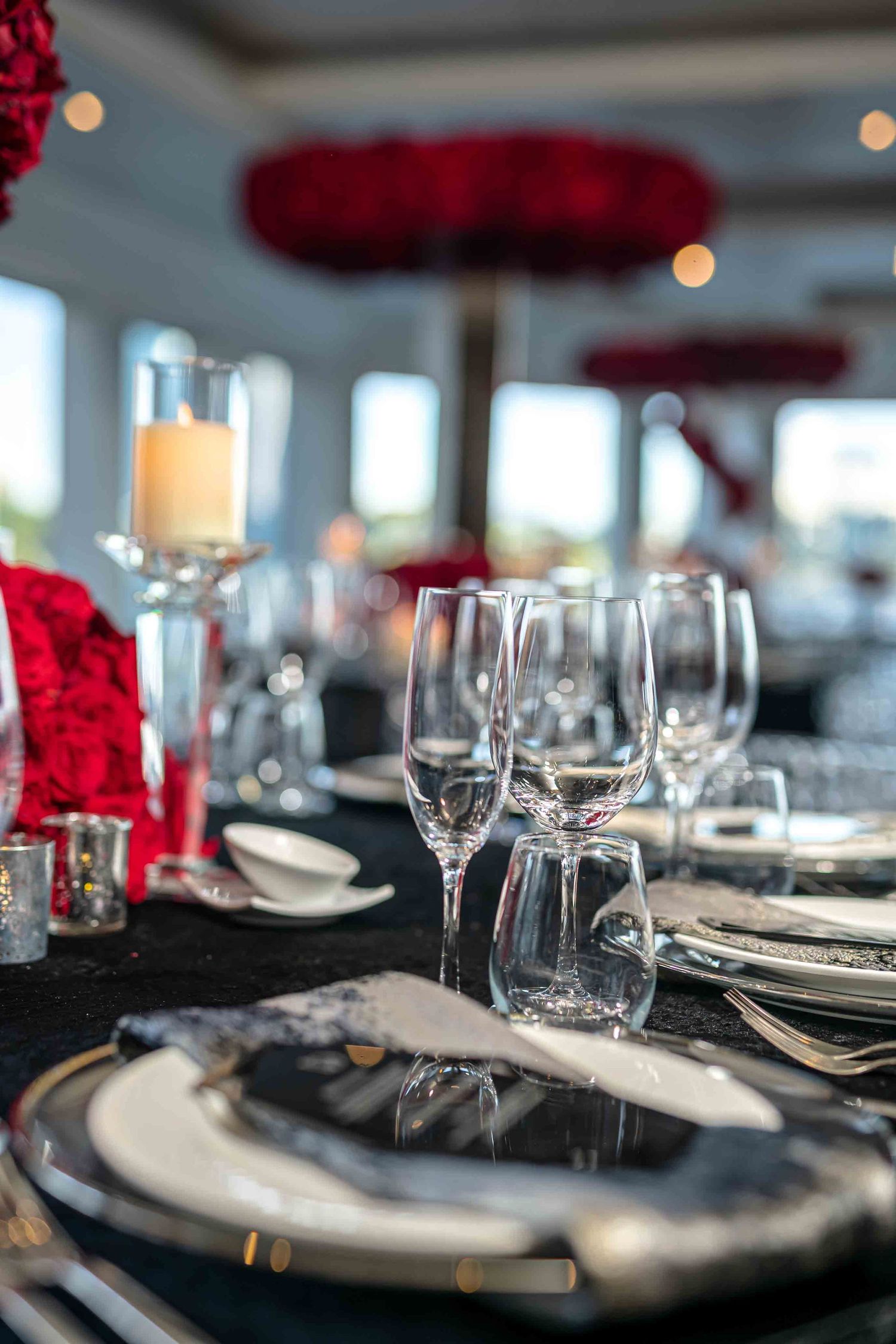 Formal place setting with crystal wine glasses and red rose centerpiece on black tablecloth on the Seafair Mega Yacht in Miami.
