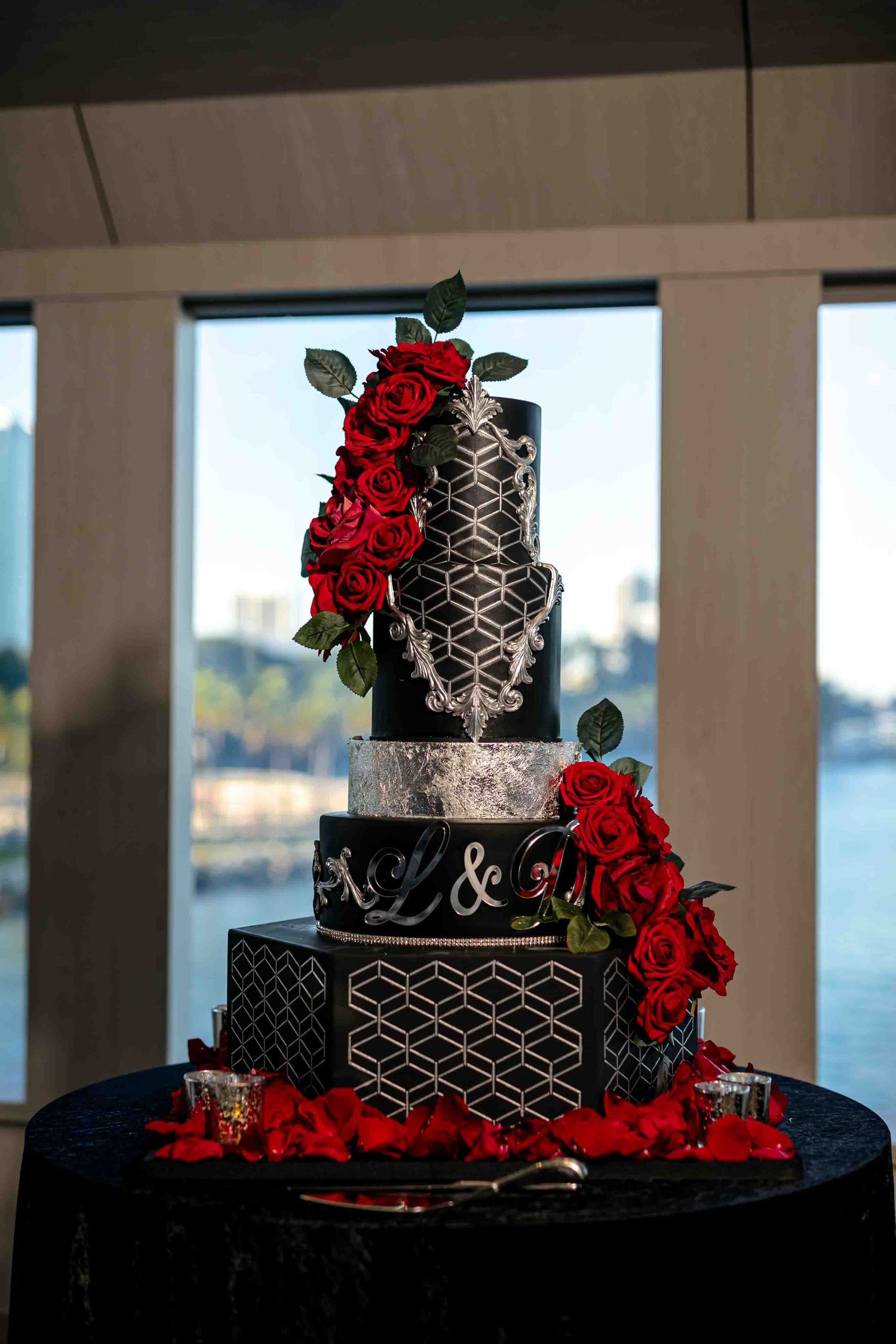 Modern black wedding cake with geometric silver patterns and fresh red rose decorations on the Seafair Mega Yacht in Miami.