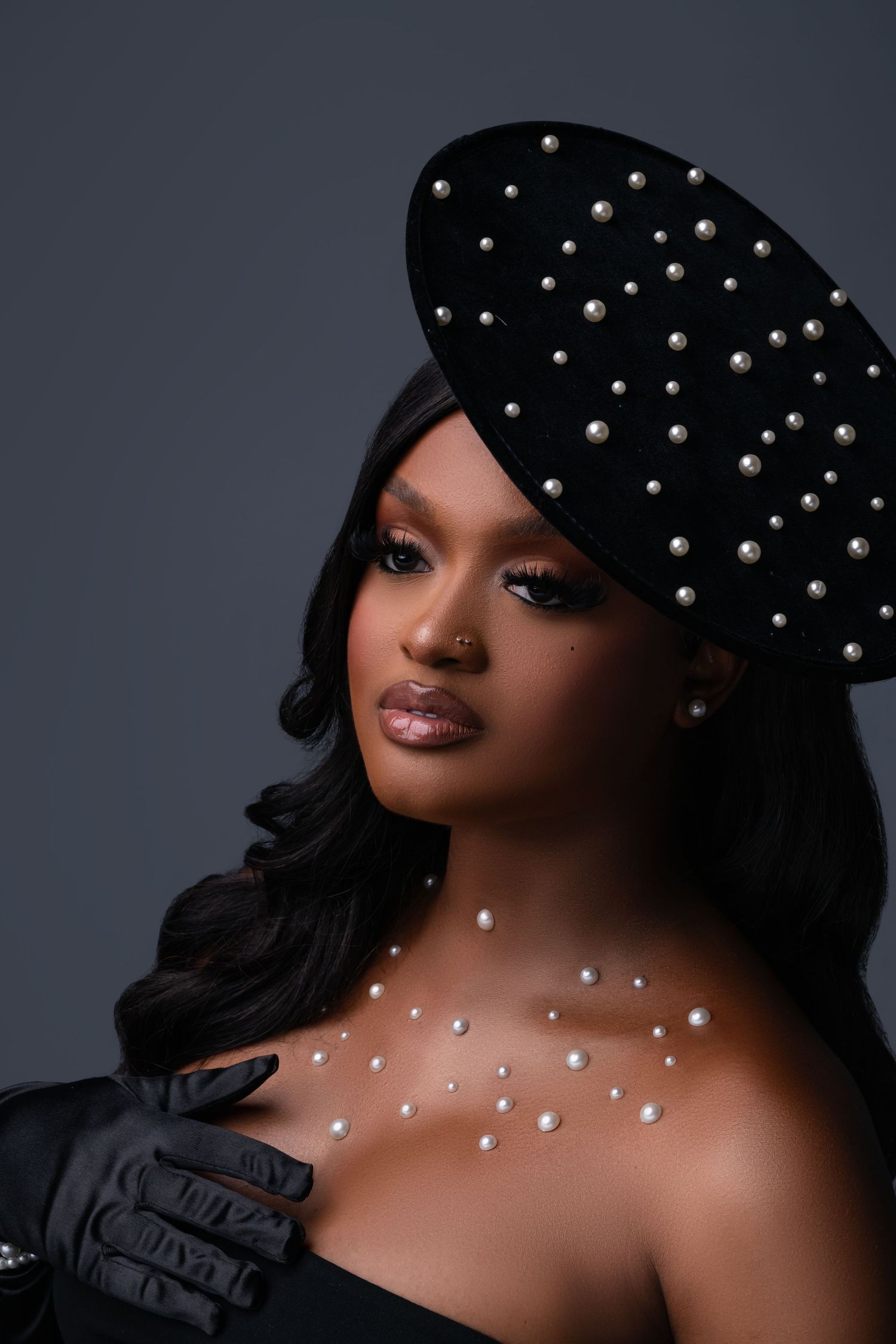 Glamorous portrait featuring a studded black cap and dramatic lighting against dark background.