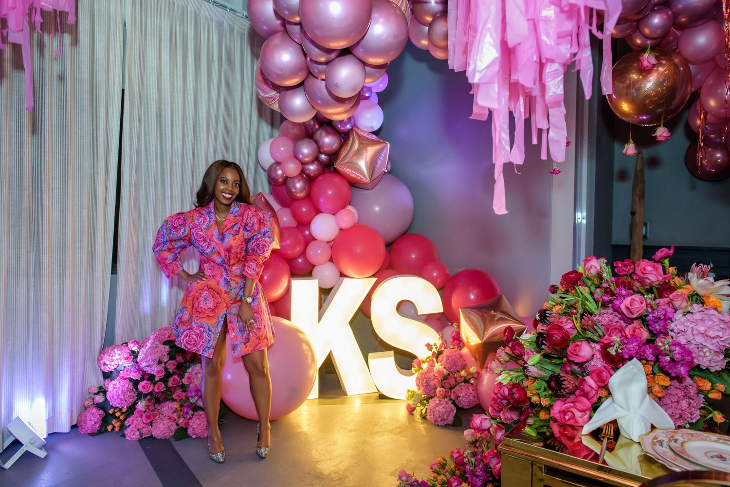 Pink balloon and floral party decor setup with illuminated KS letters creating an elegant celebration backdrop.
