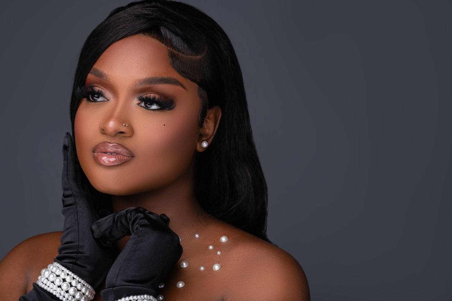 Glamorous beauty portrait featuring sparkly jewelry and dramatic makeup against dark background.