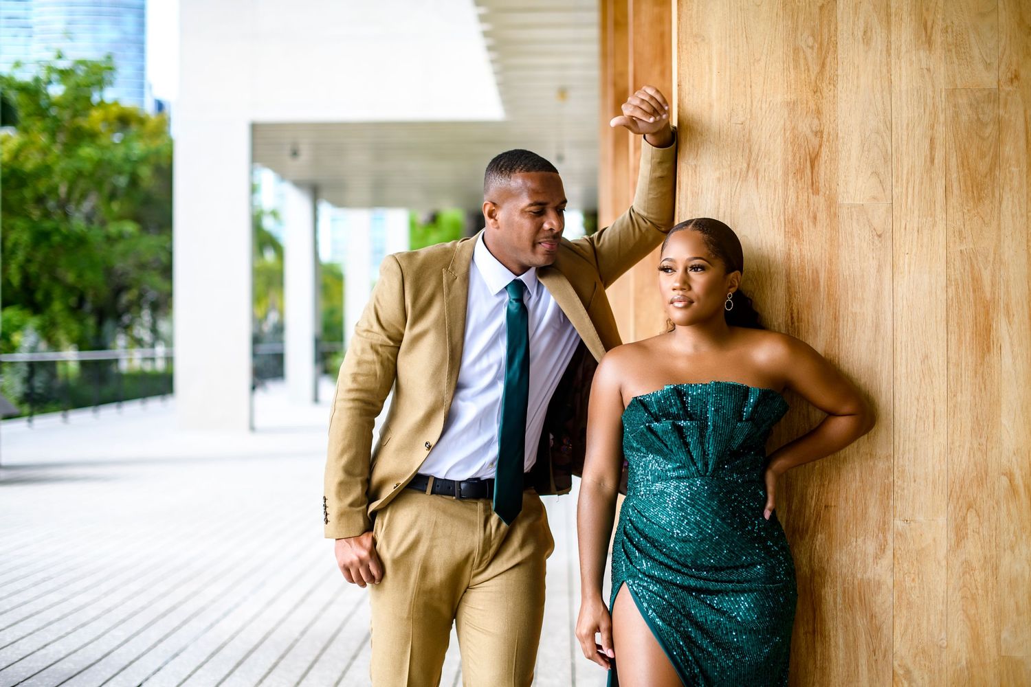 Fashionable couple posing against wooden wall in modern architectural setting.