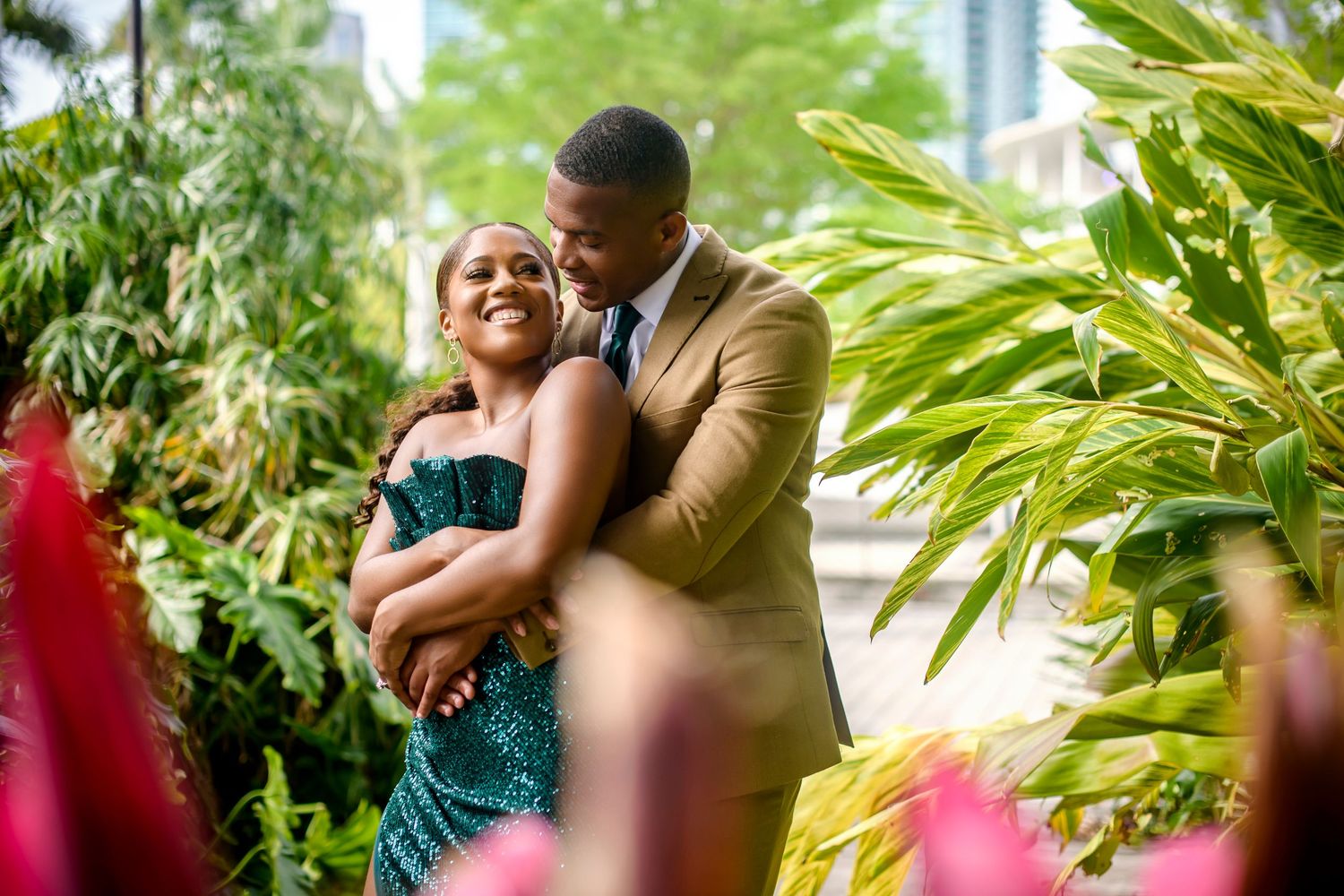 A romantic moment captured between a couple in formal wear among tropical plants.