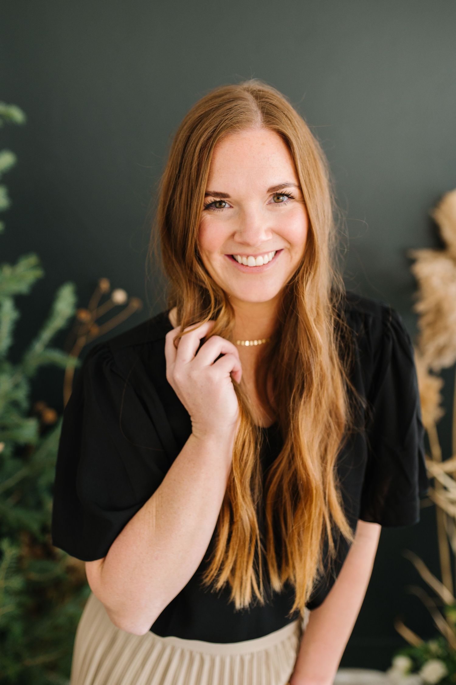 Professional portrait against dark wall with indoor plants.