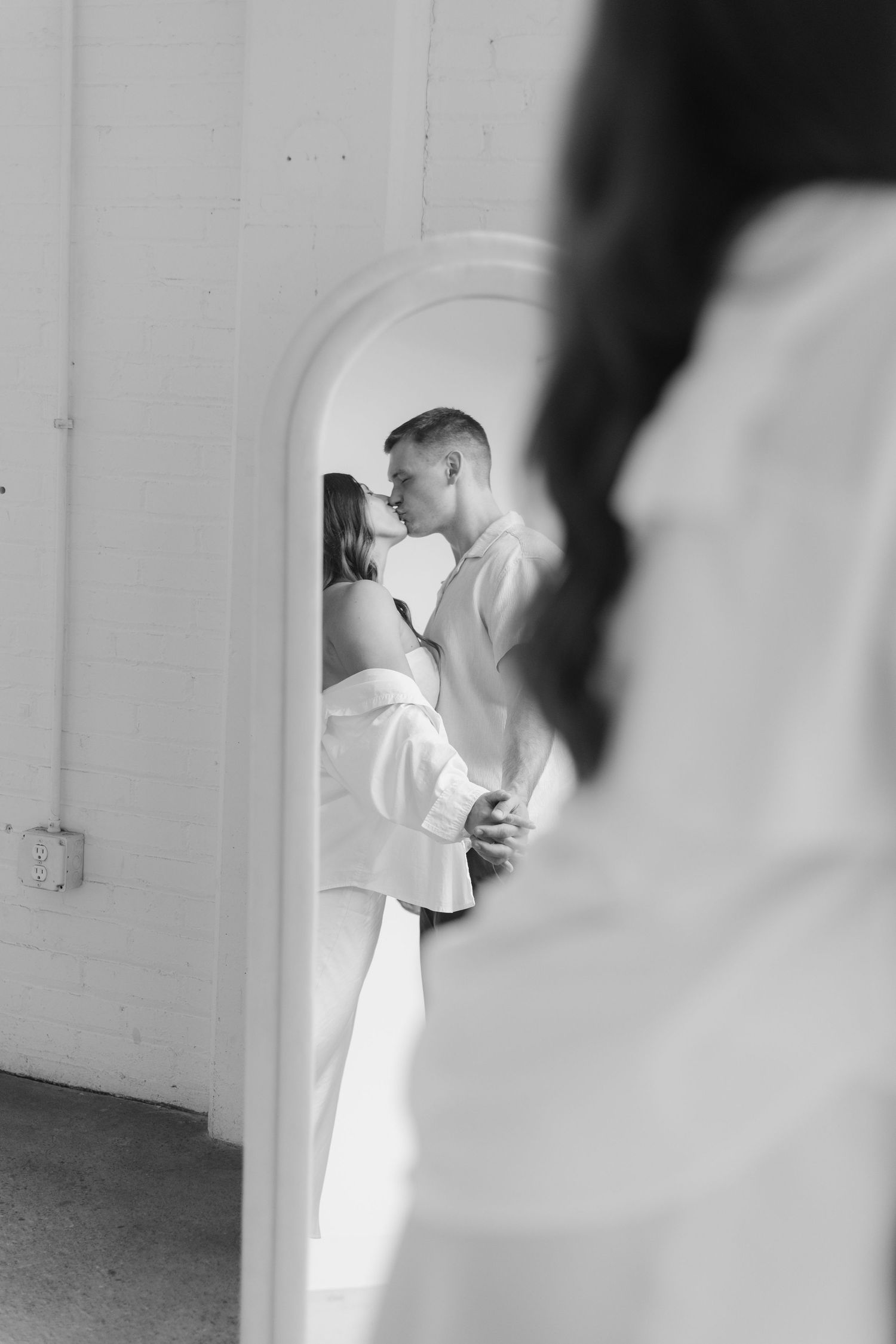 Couple embracing in soft natural light at Abide Studio in Minneapolis, MN, with minimalist white walls and warm, cozy tones