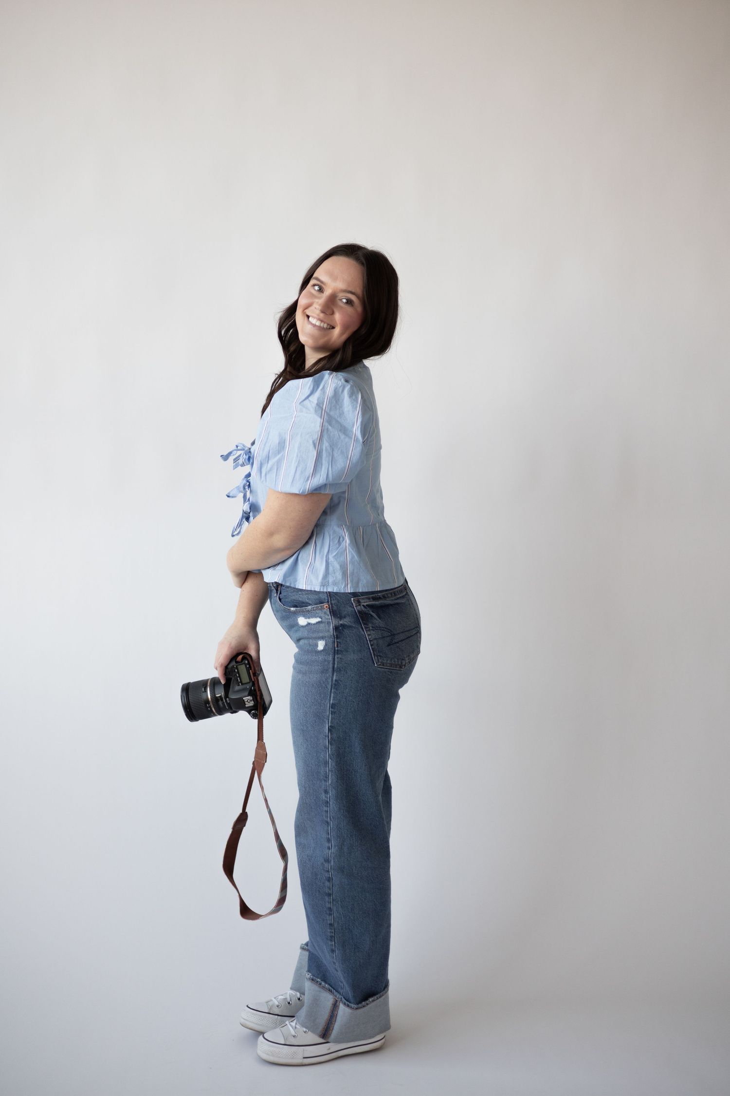 Photographer posing with camera at Abide Studio in Minneapolis, MN, surrounded by natural light, for a professional branding session