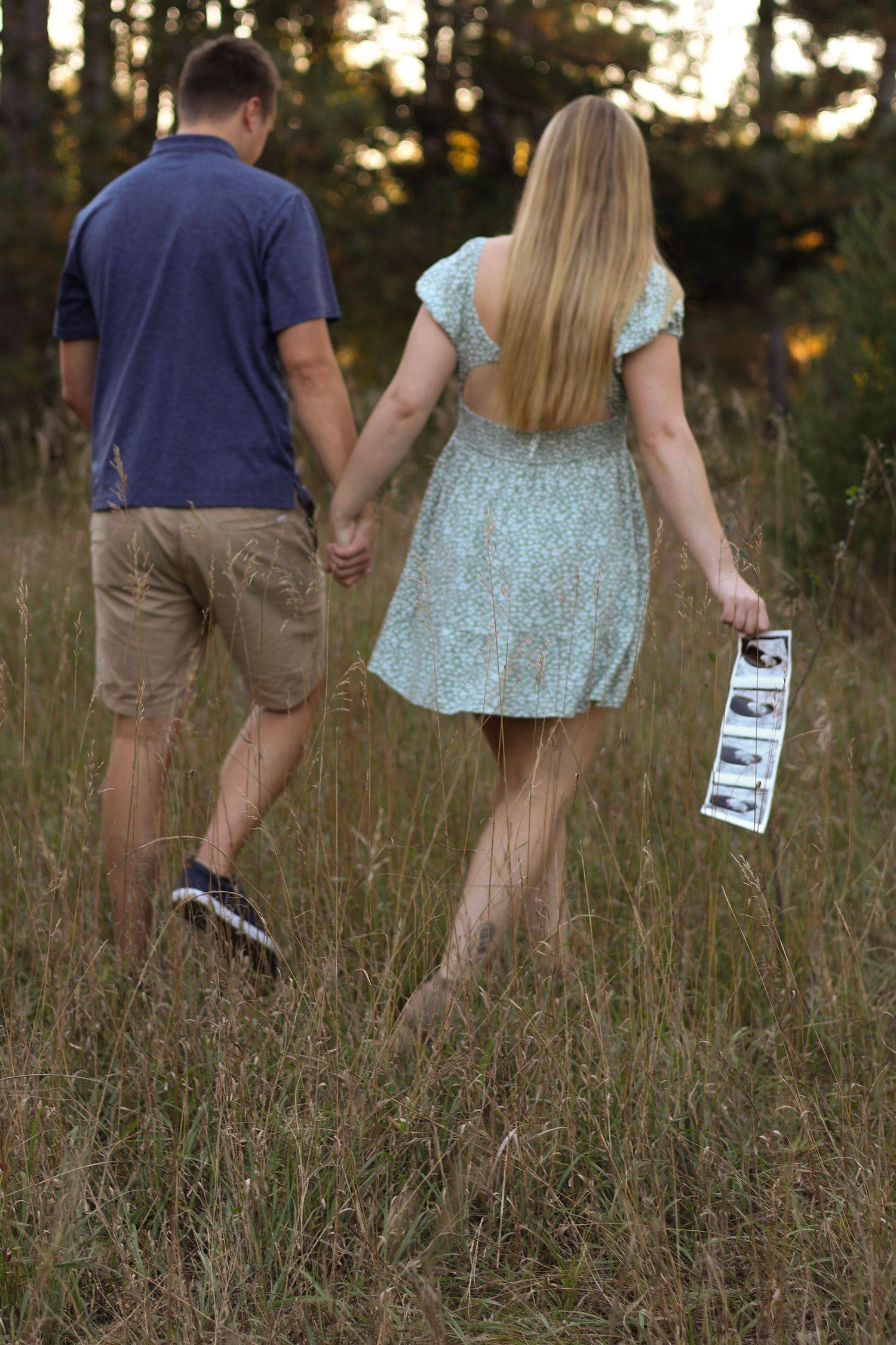 Expecting couple smiling and holding ultrasound photo near colorful fall foliage at Montissippi Park in Monticello, Minnesota