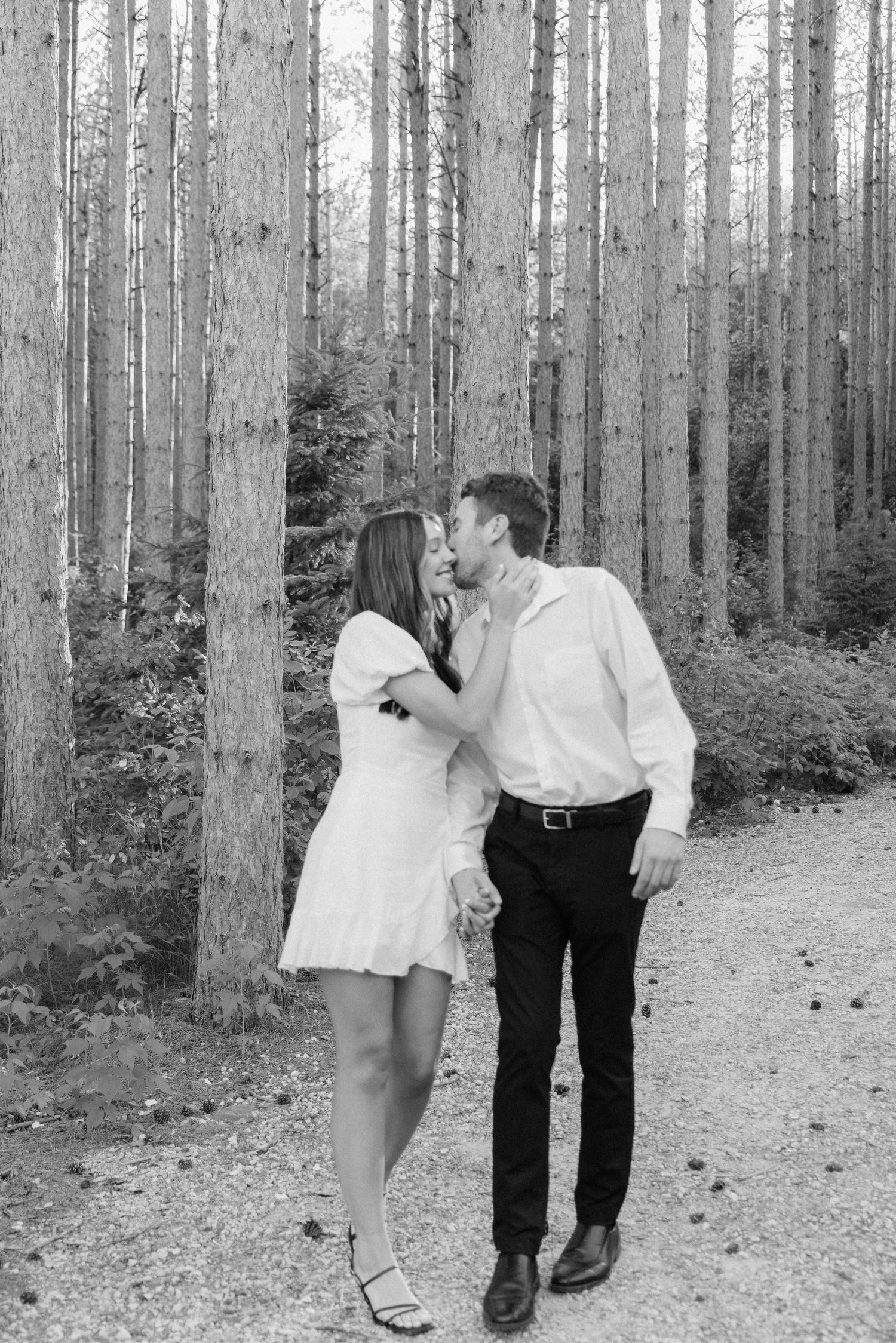 Couple walking hand-in-hand along a wooded path at pinewood wedding venue in Cambridge Minnesota, creating a warm and intimate moment.