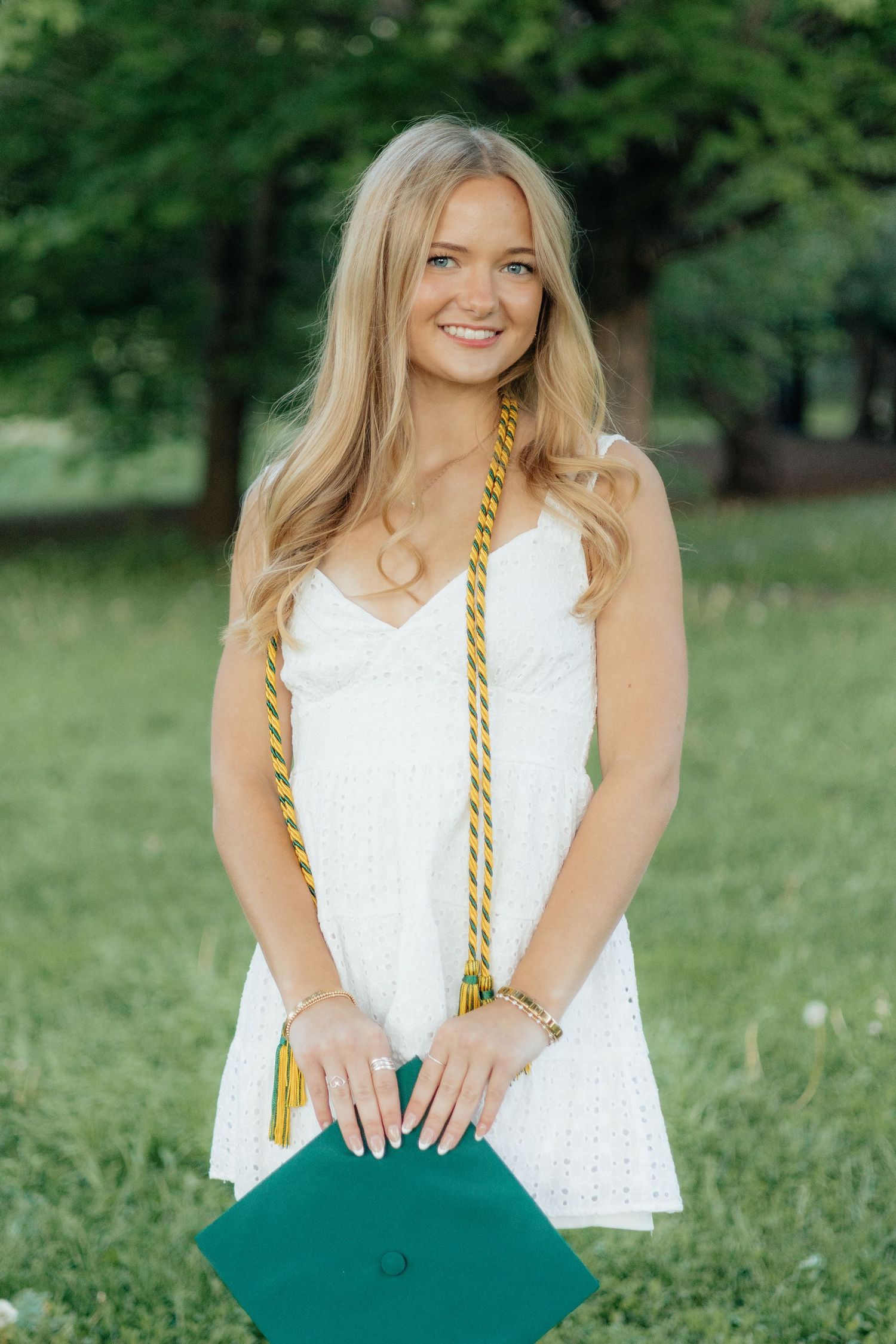 High school graduate smiling and posing among blooming roses at Lyndale Park Rose Garden in Minneapolis, MN, surrounded by vibrant flowers a
