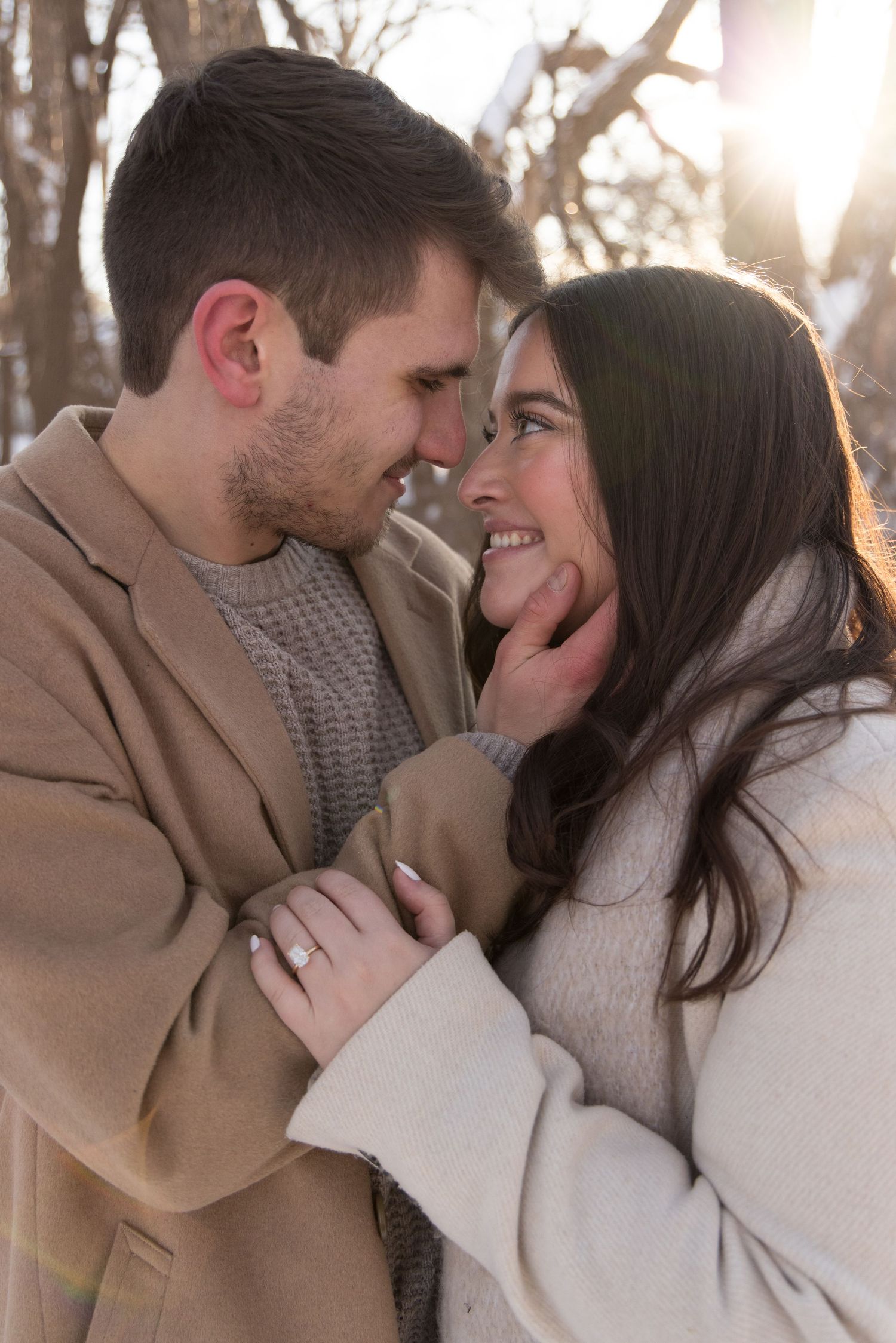 Engaged couple bundled in winter coats, laughing together on a snowy street in the North Loop of Minneapolis