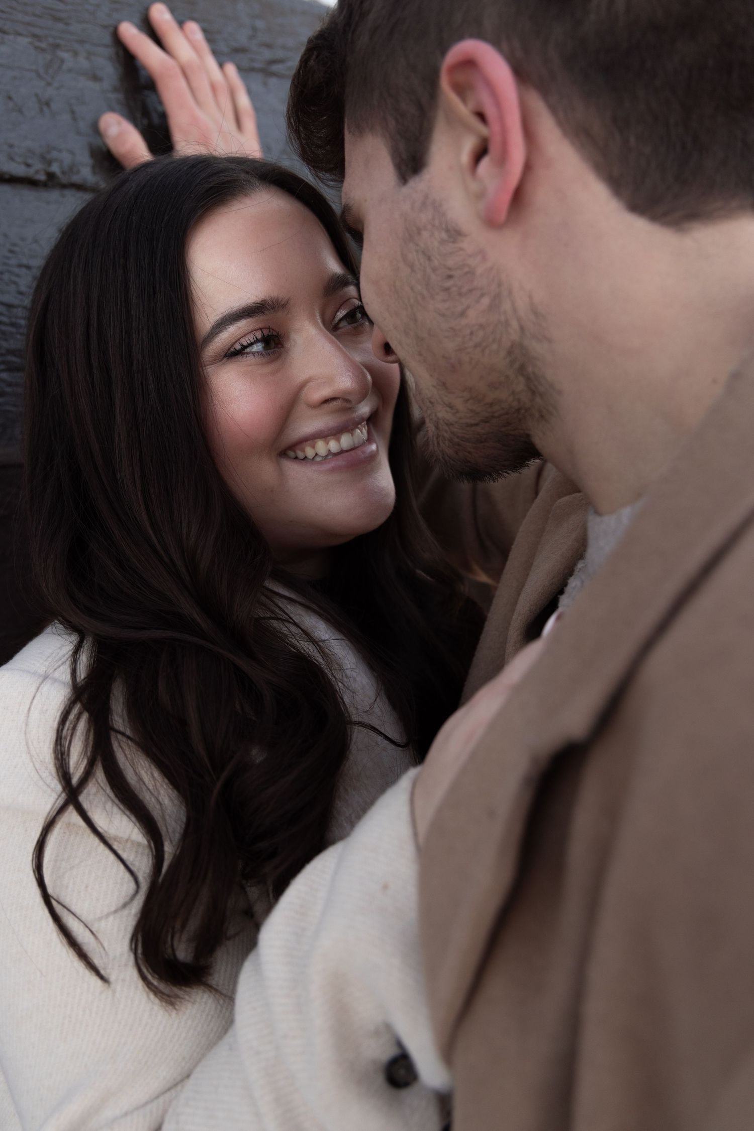Engaged couple bundled in winter coats, laughing together on a snowy street in the North Loop of Minneapolis