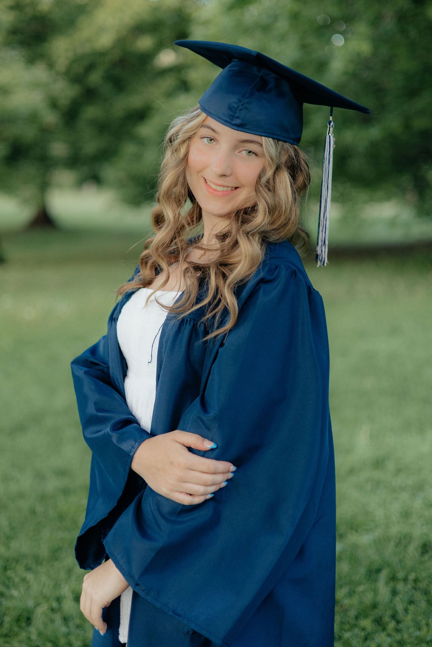High school graduate smiling and posing among blooming roses at Lyndale Park Rose Garden in Minneapolis, MN, surrounded by vibrant flowers a