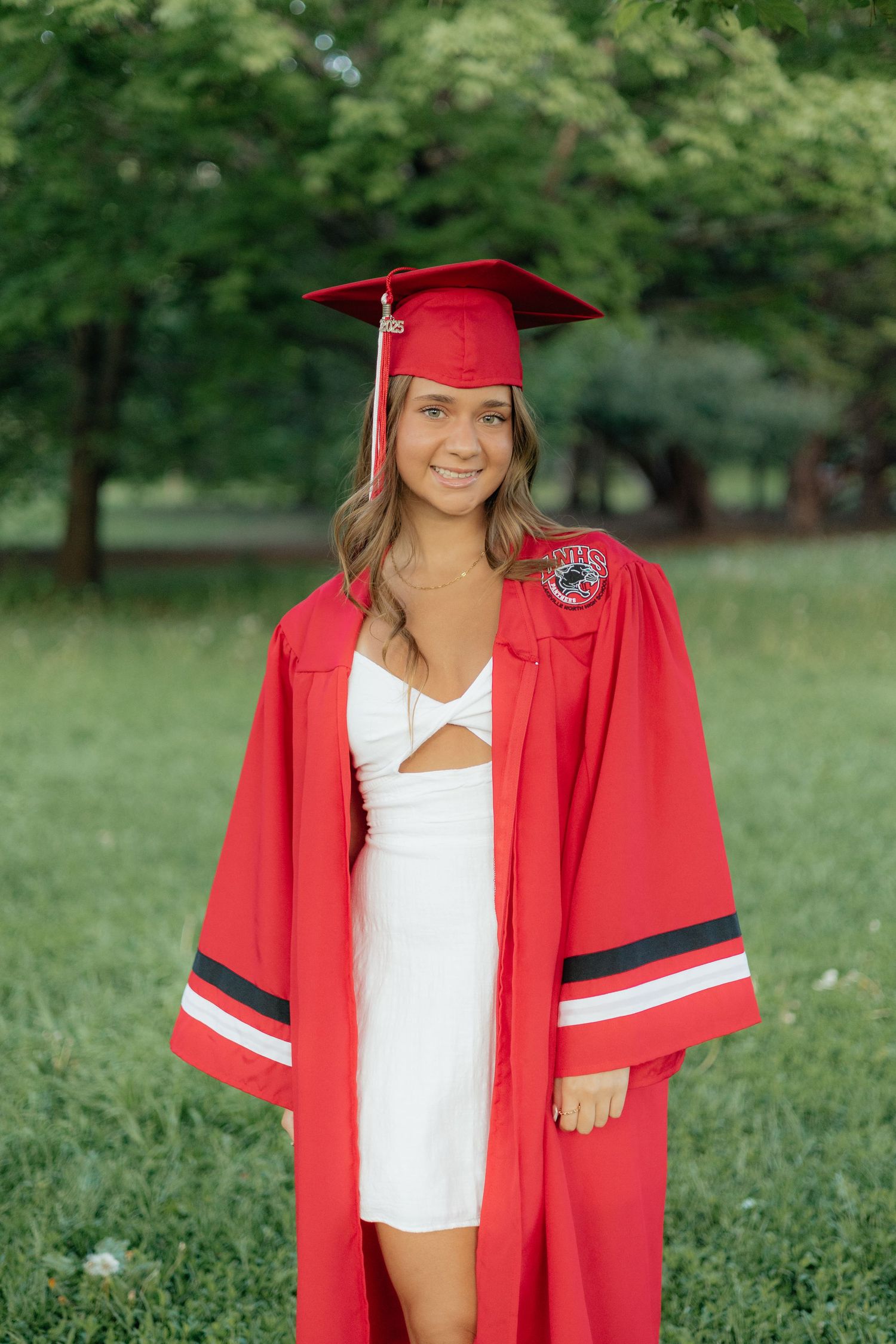 High school graduate smiling and posing among blooming roses at Lyndale Park Rose Garden in Minneapolis, MN, surrounded by vibrant flowers a