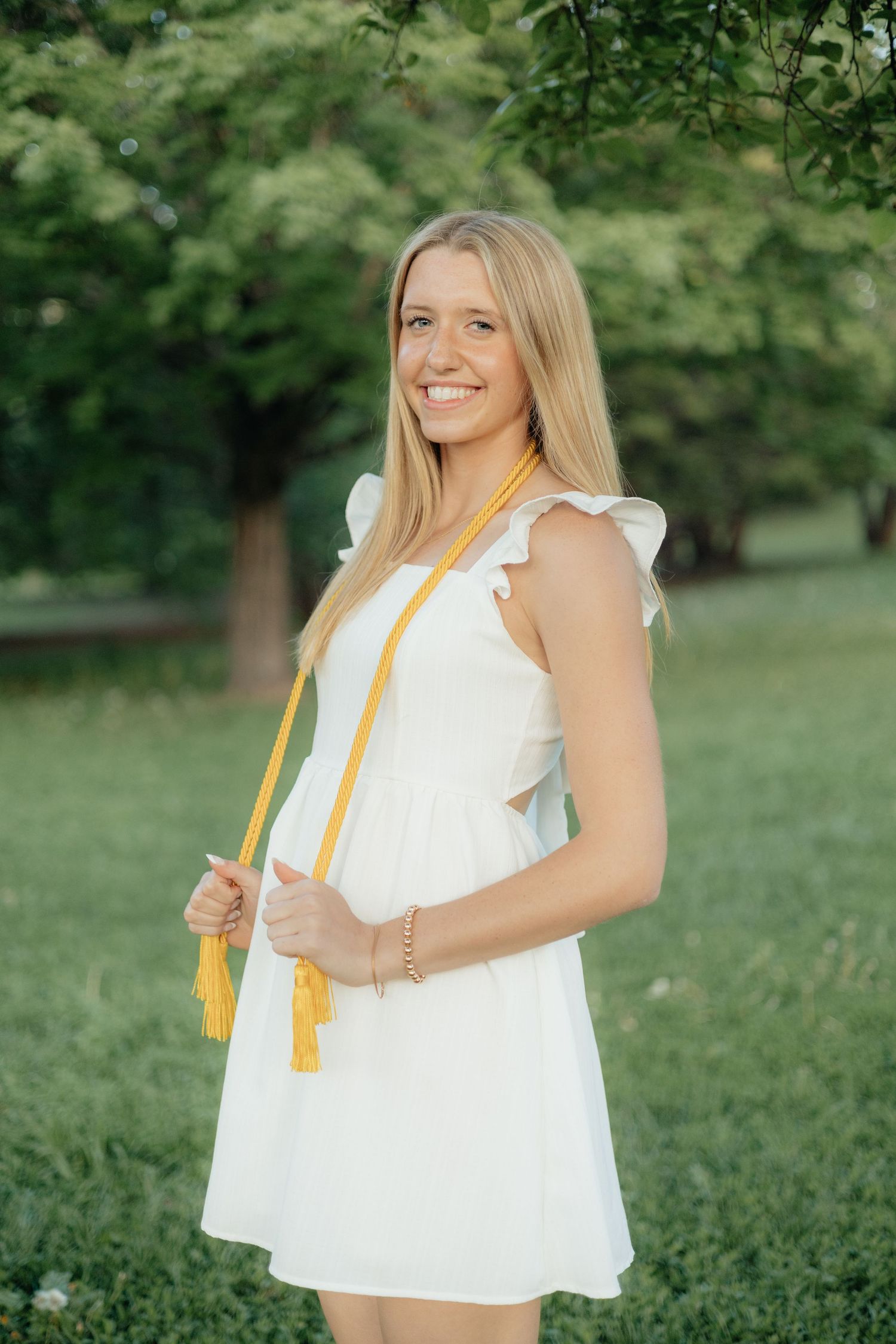 High school graduate smiling and posing among blooming roses at Lyndale Park Rose Garden in Minneapolis, MN, surrounded by vibrant flowers a