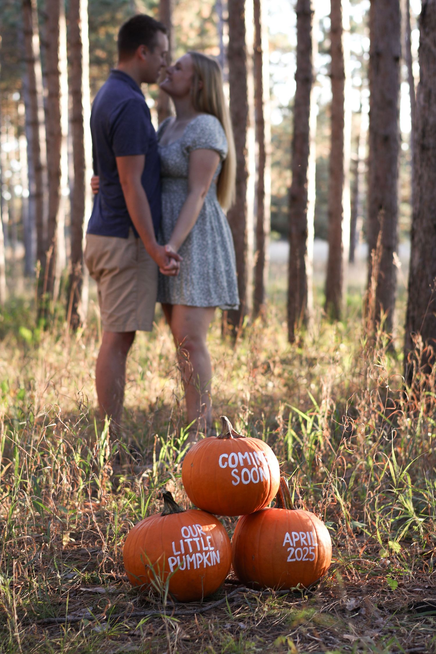 Expecting couple smiling and holding ultrasound photo near colorful fall foliage at Montissippi Park in Monticello, Minnesota