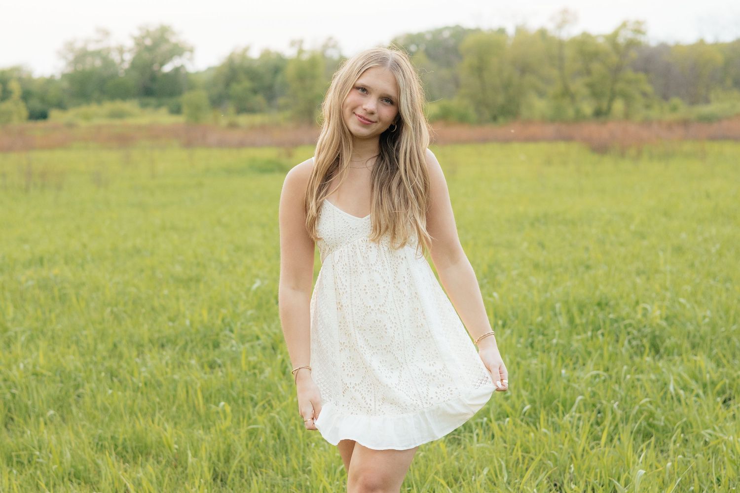 High school senior smiling and posing among blooming roses at Lyndale Park Rose Garden in Minneapolis, MN, surrounded by vibrant flowers and