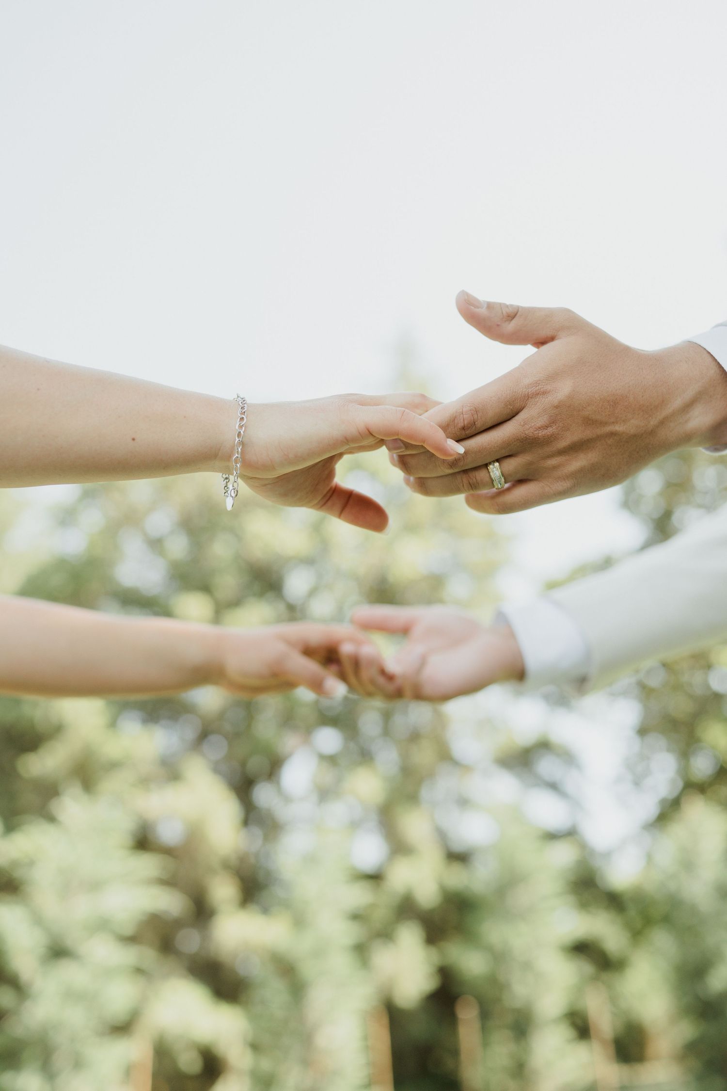 Close-up of hands gently touching during an intimate wedding moment outdoors.
