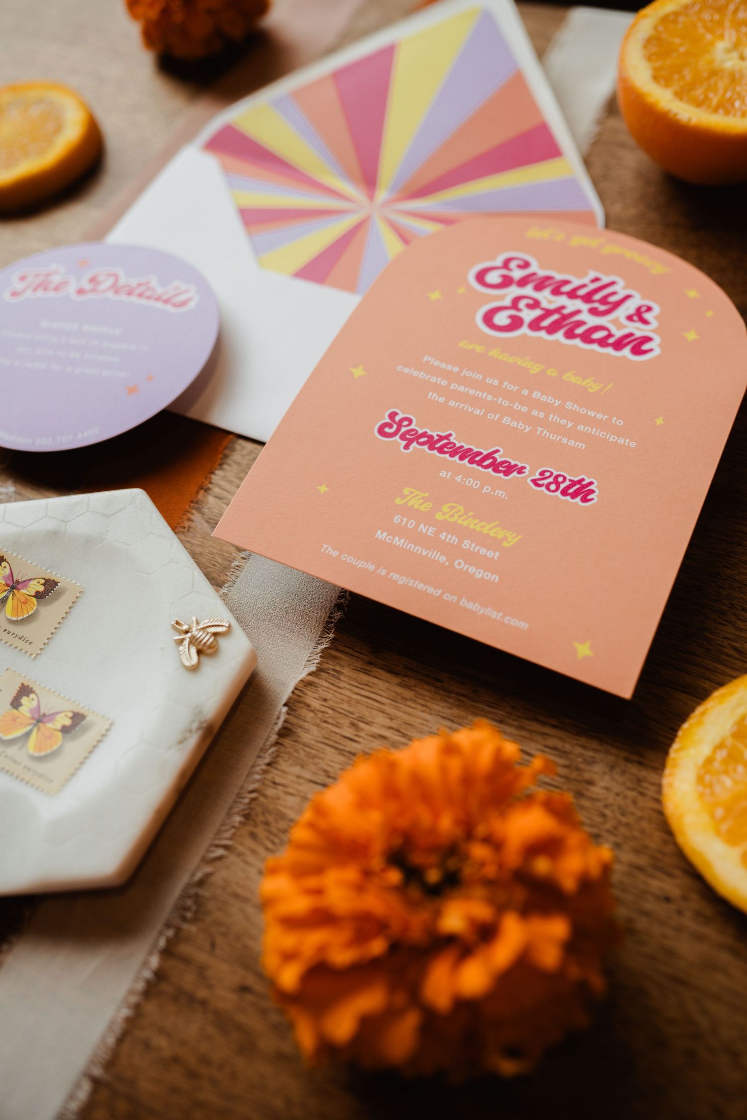 Close-up of peach and pink wedding invitation with butterfly stamps and marigold flowers.
