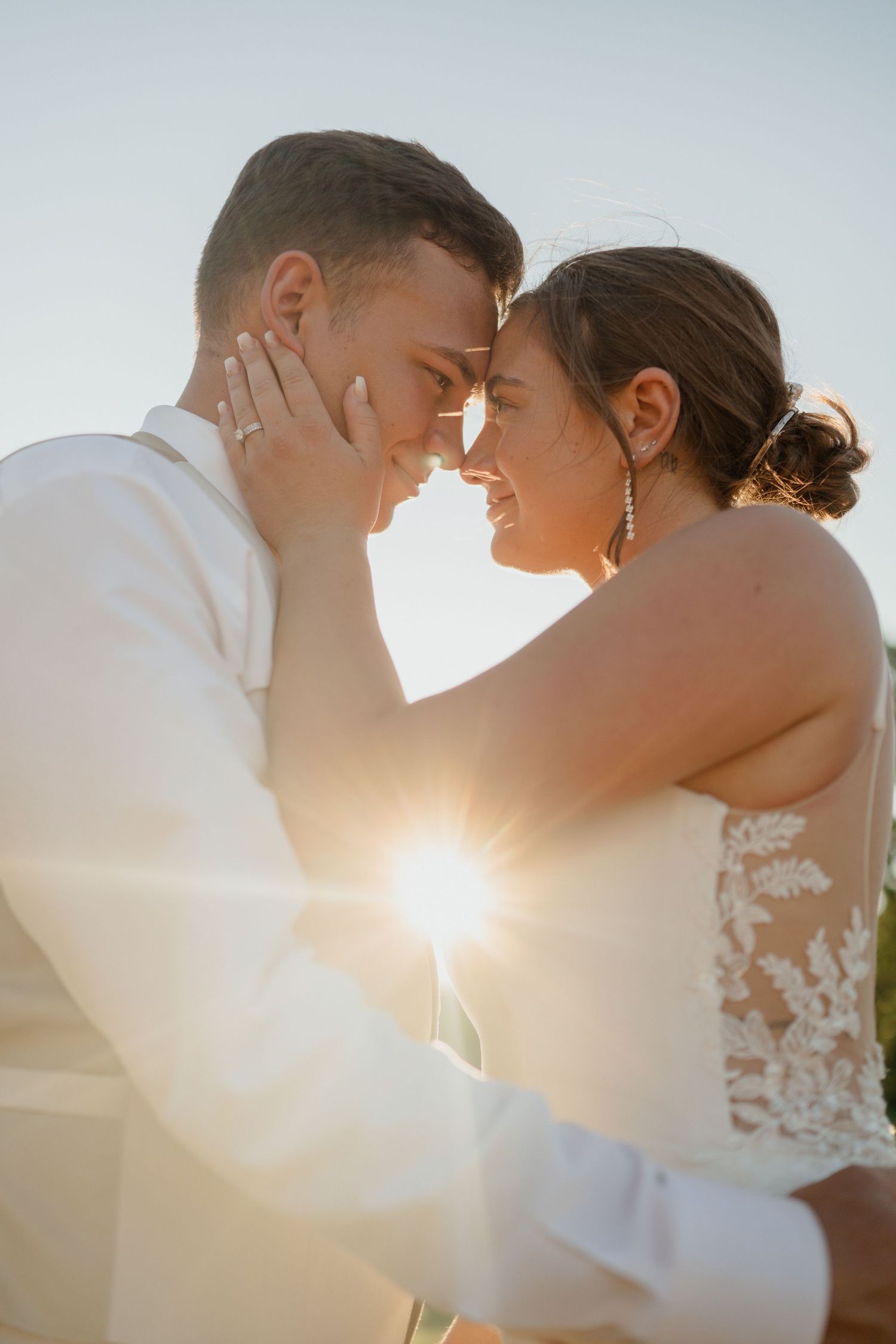 A romantic sunset moment between newlyweds in white wedding attire.