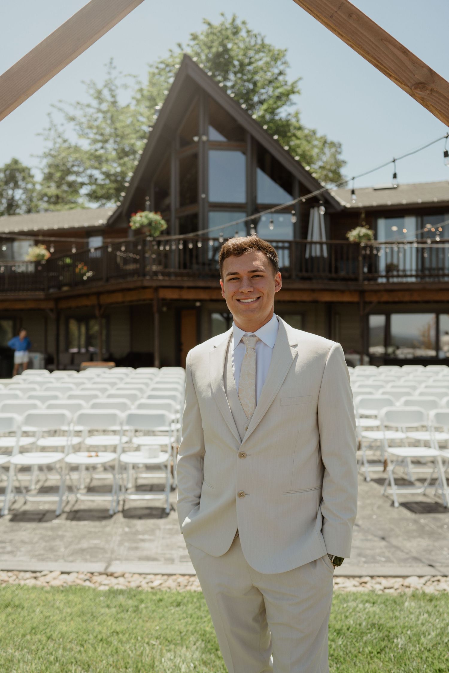 A wedding venue setup with white chairs and an A-frame house in the background.