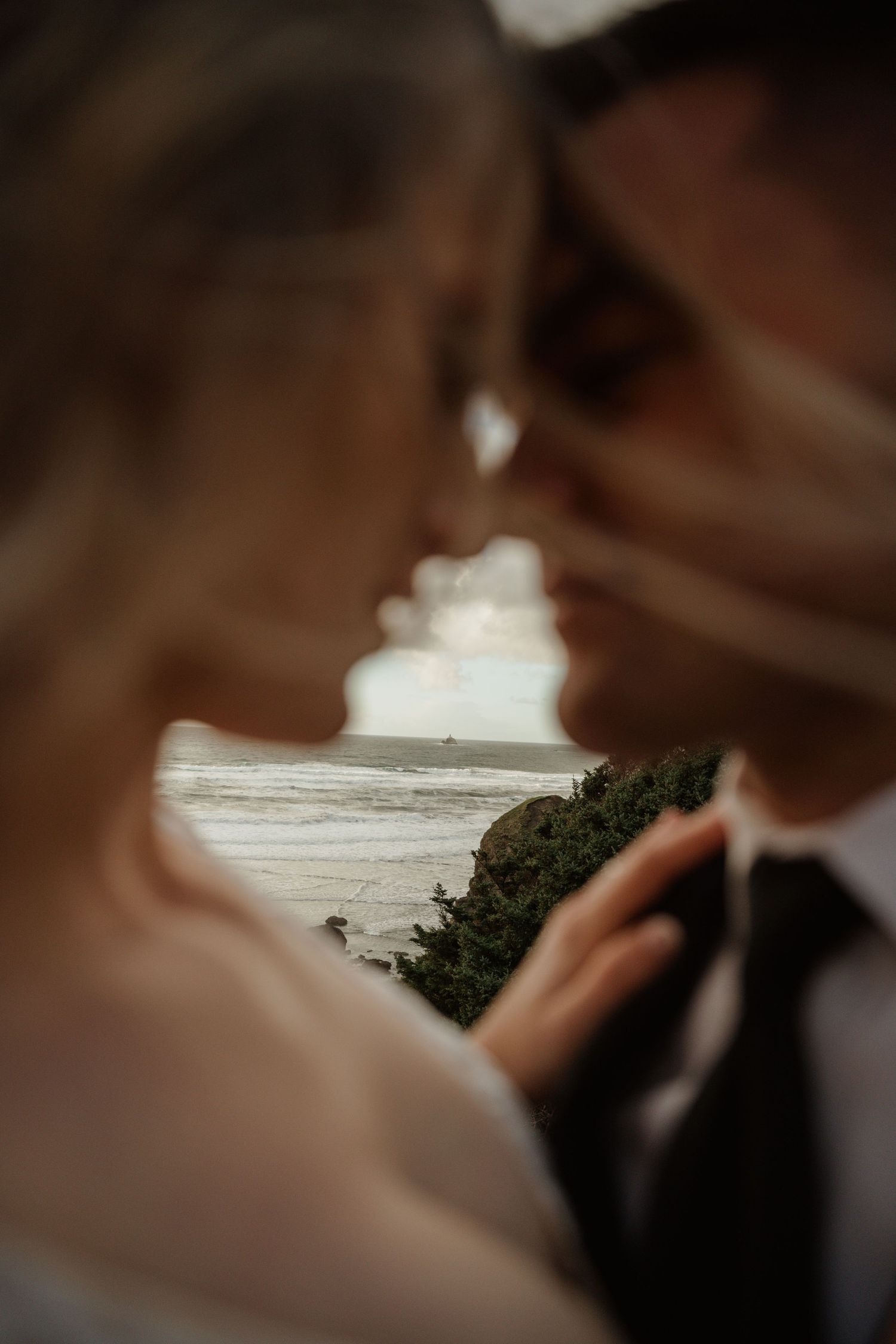 An intimate closeup of a couple with ocean waves visible in the background.