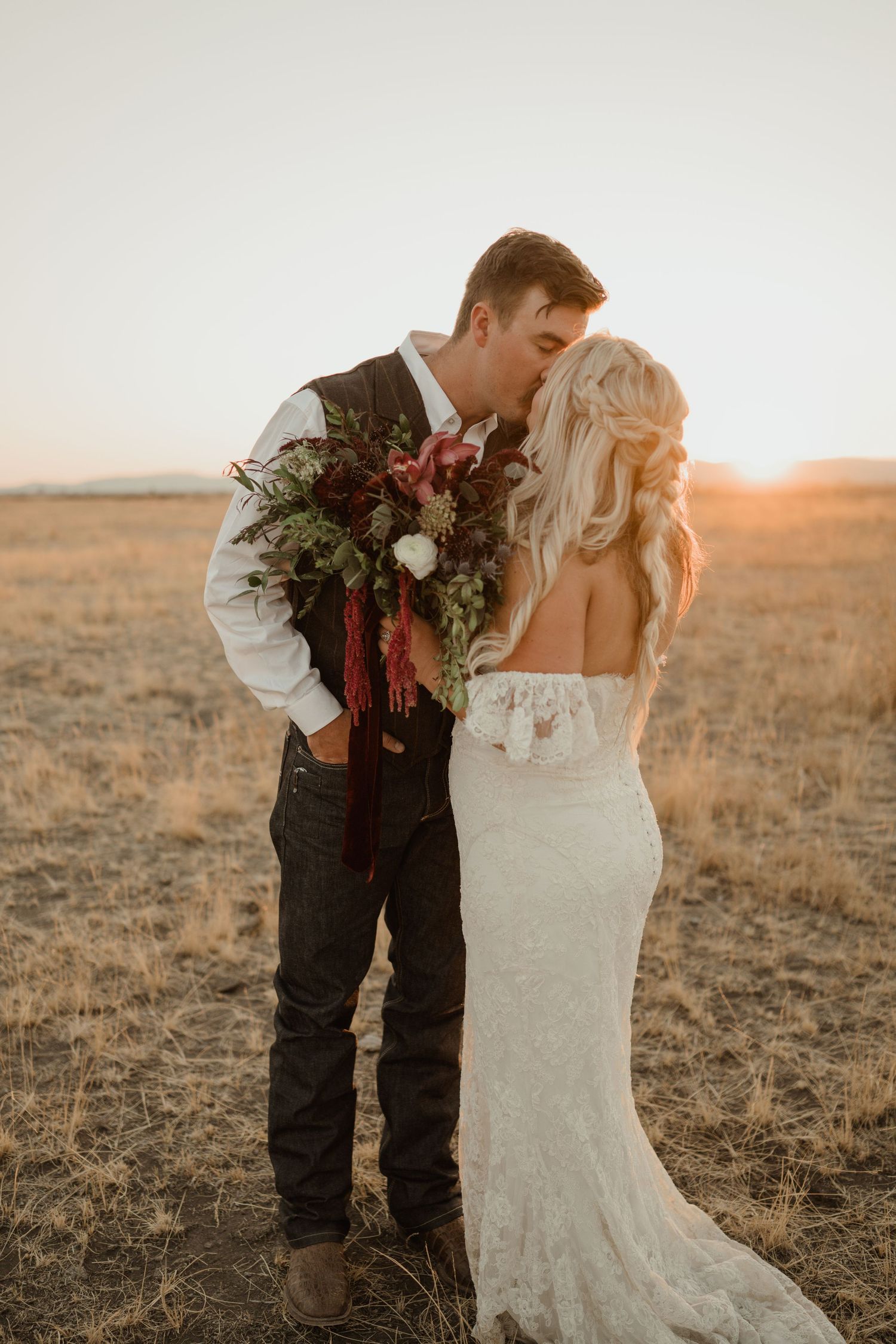 A tender wedding moment captured in golden light with burgundy floral bouquet.