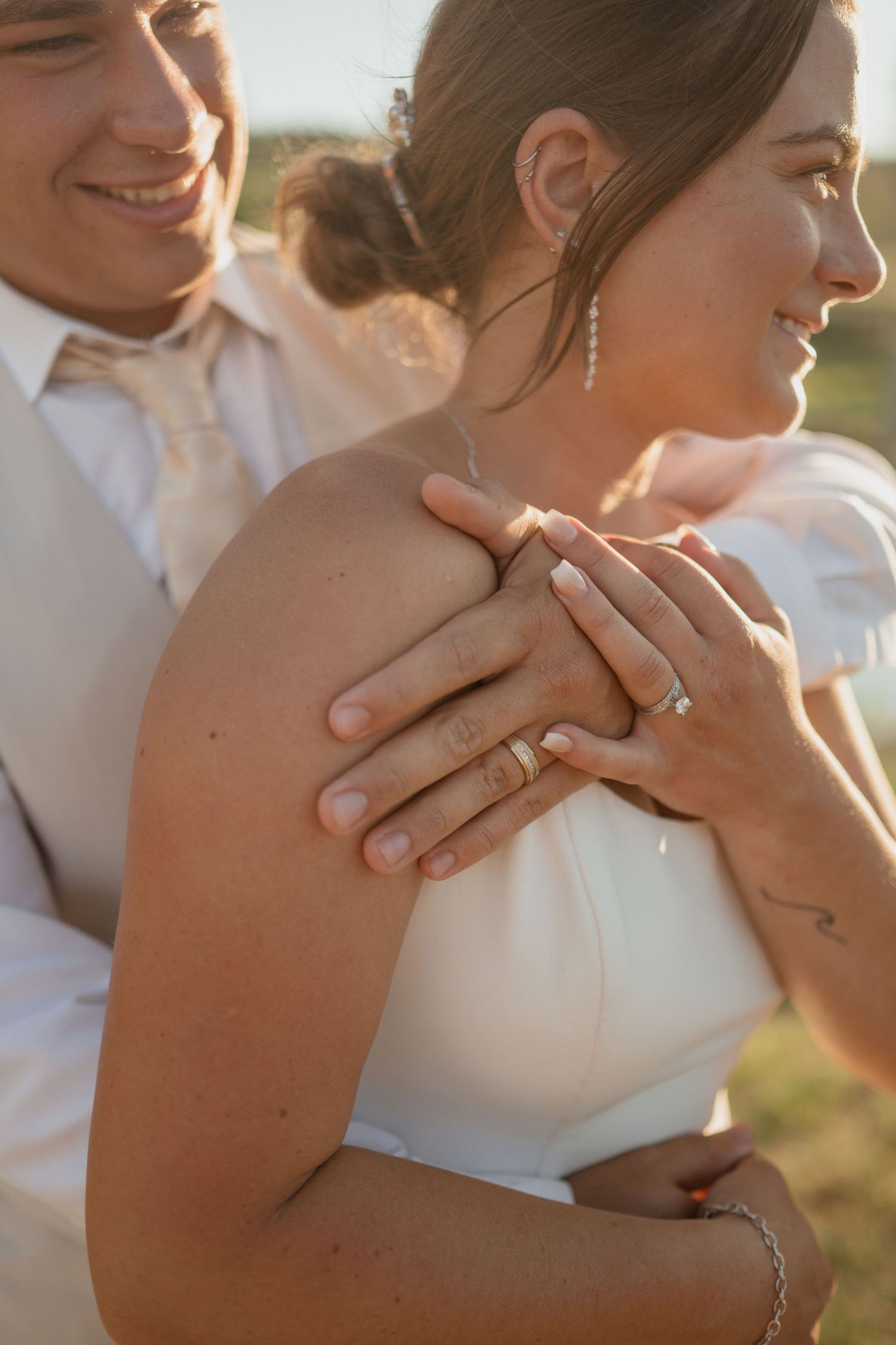 Close-up of newlyweds sharing an intimate embrace with rings visible.