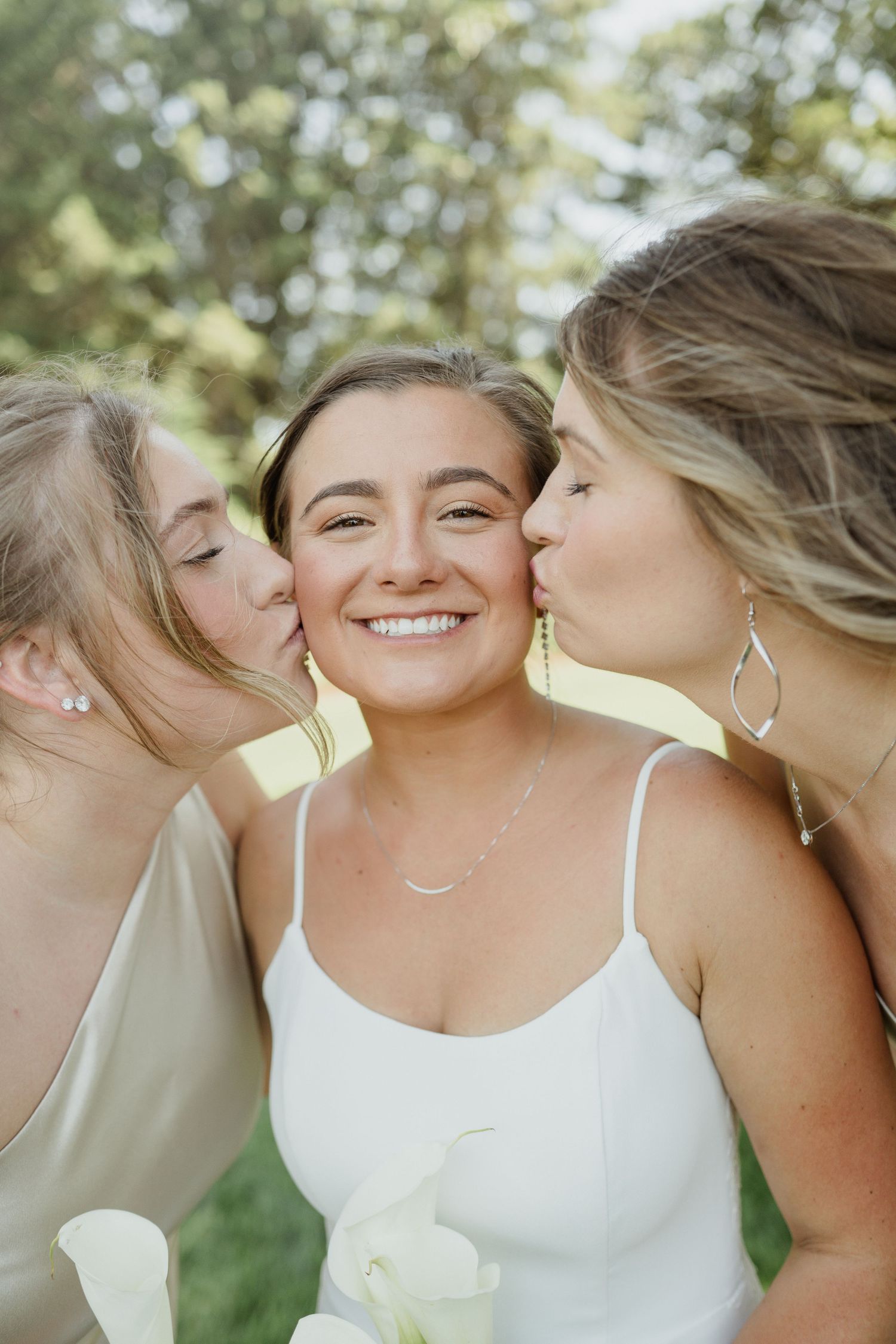 A sweet moment captured between friends in formal attire at an outdoor celebration.