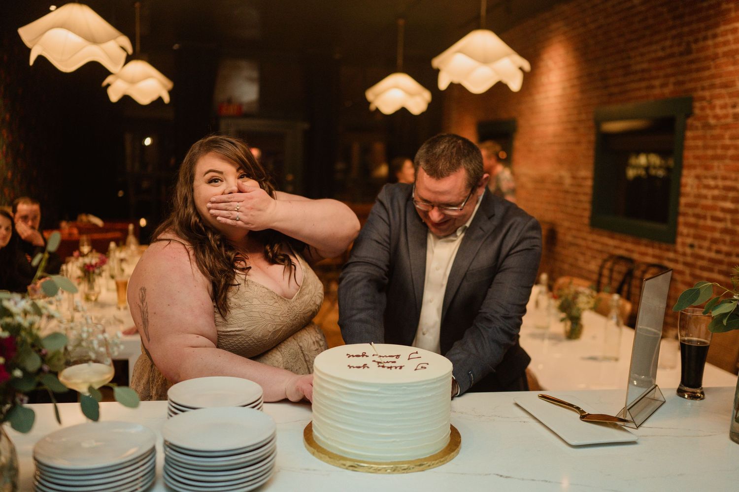A couple shares a playful moment while cutting their wedding cake at the reception.